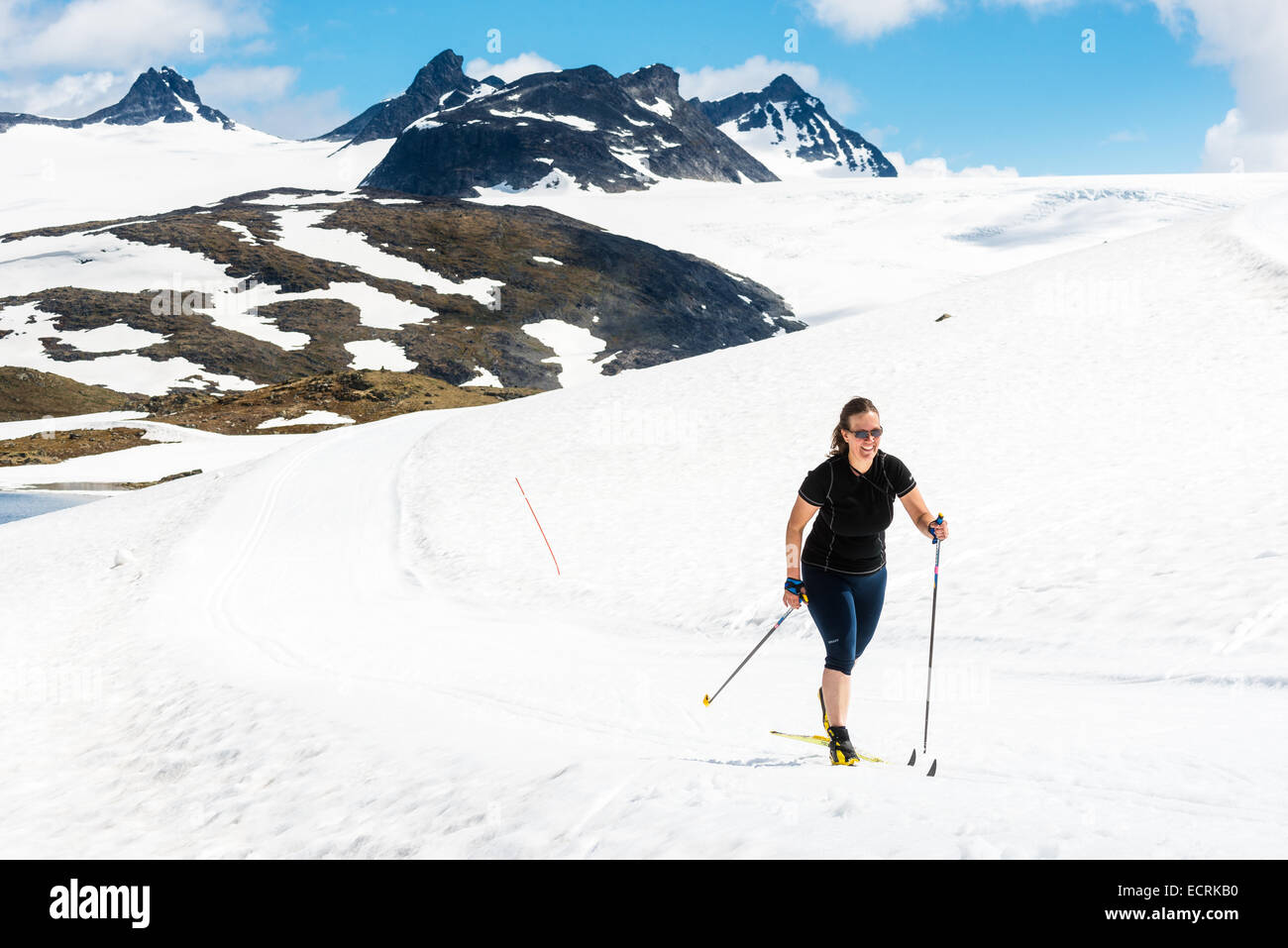 Frau in Sommerkleidung Skifahren an der Spitze eines Berges Stockfoto