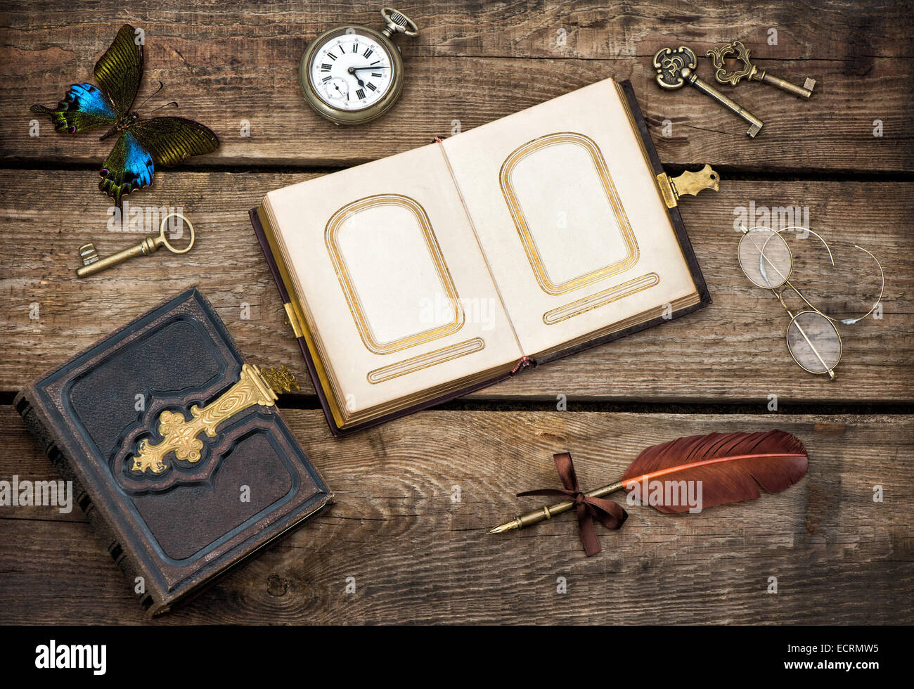 Antiquarische Bücher, Accessoires und Schmetterling über rustikalen hölzernen Hintergrund zu schreiben. Vintage Schlüssel, Taschenuhr, Gläser und Feder Stockfoto
