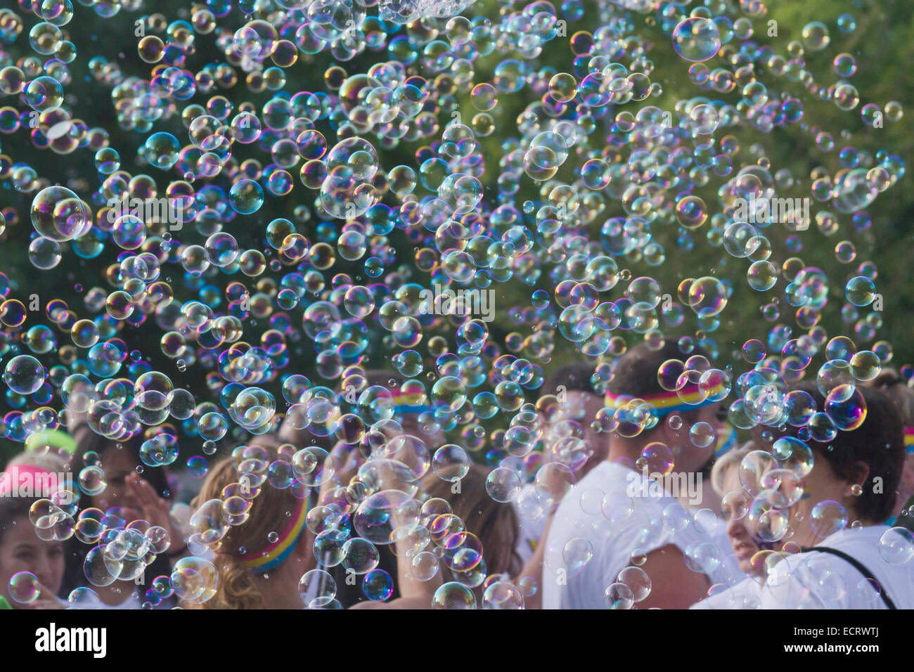 Glückliche Farbe führen Sie die Teilnehmer durch eine bunte Wolke von Seifenblasen umgeben Stockfoto