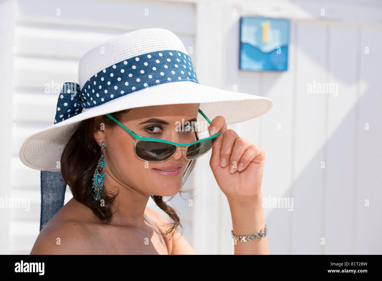 Frau mit Hut, Blick über den Tellerrand ihrer Sonnenbrille, Adria, Senigallia, Provinz Ancona, Marken, Italien Stockfoto