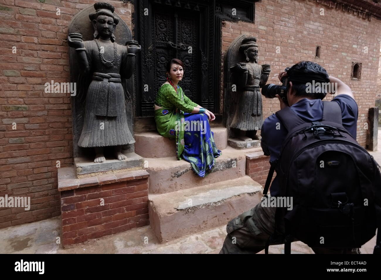 Chinesische Touristen in die Kamera posieren inmitten gemeißelte Figuren verzieren einer der Eingänge zum königlichen Palast Komplex in Layaku Durbar Square liegt ein Konglomerat von Pagode und Shikhara - Stil Tempel, meist auf die hinduistischen Götter und Göttinnen in der Stadt Bhaktapur auch als Khwopa in Nepal bekannt Stockfoto