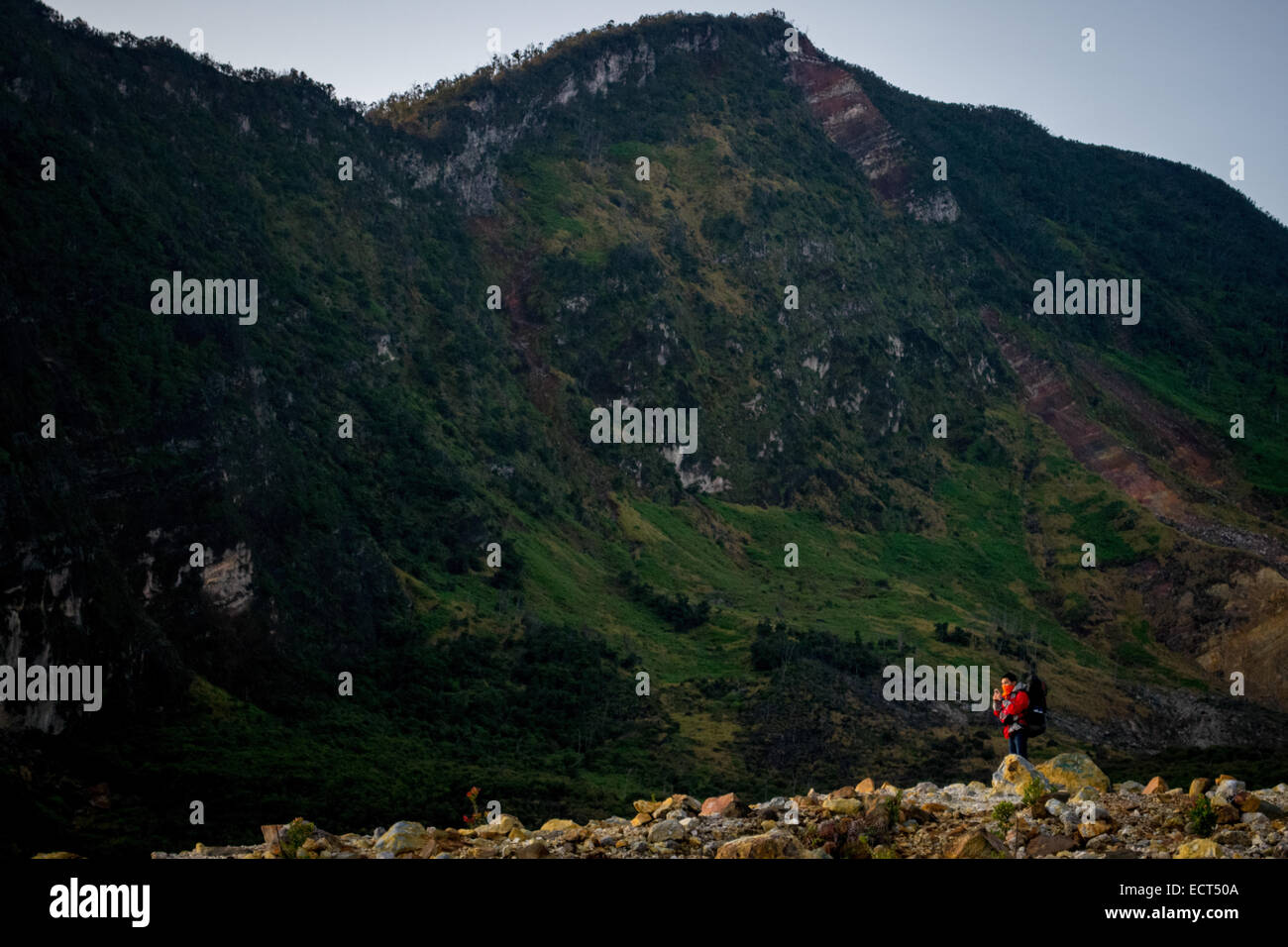 Ein Bergsteiger in rote Jacke mit der Caldera-Wand des Mount Papandayan im Hintergrund. Stockfoto
