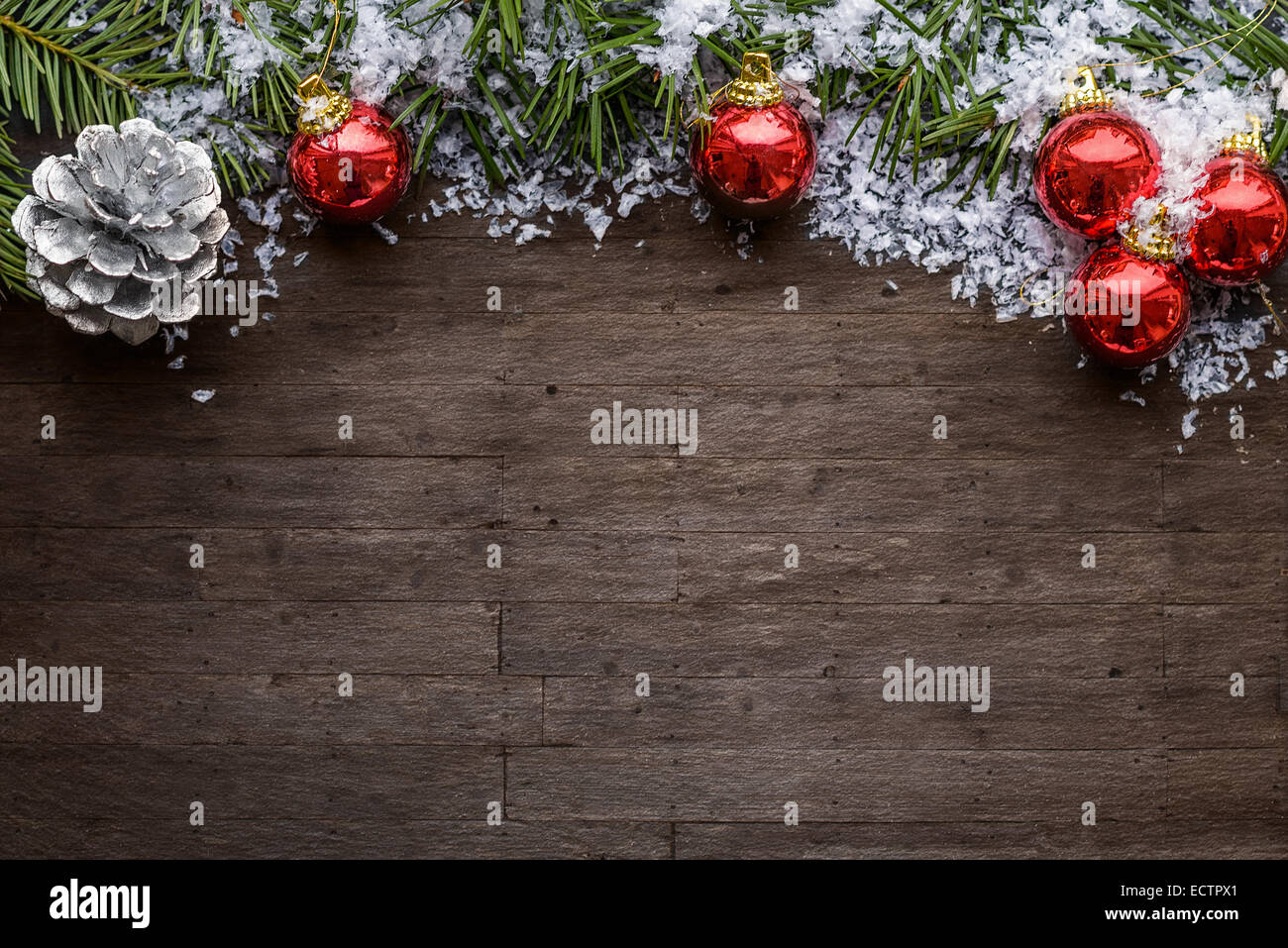 Weihnachten Hintergrund mit bunten roten Kugeln, ein Silber dekorative Tannenzapfen und grünen Tannenzweigen über eine strukturierte graue backg Stockfoto
