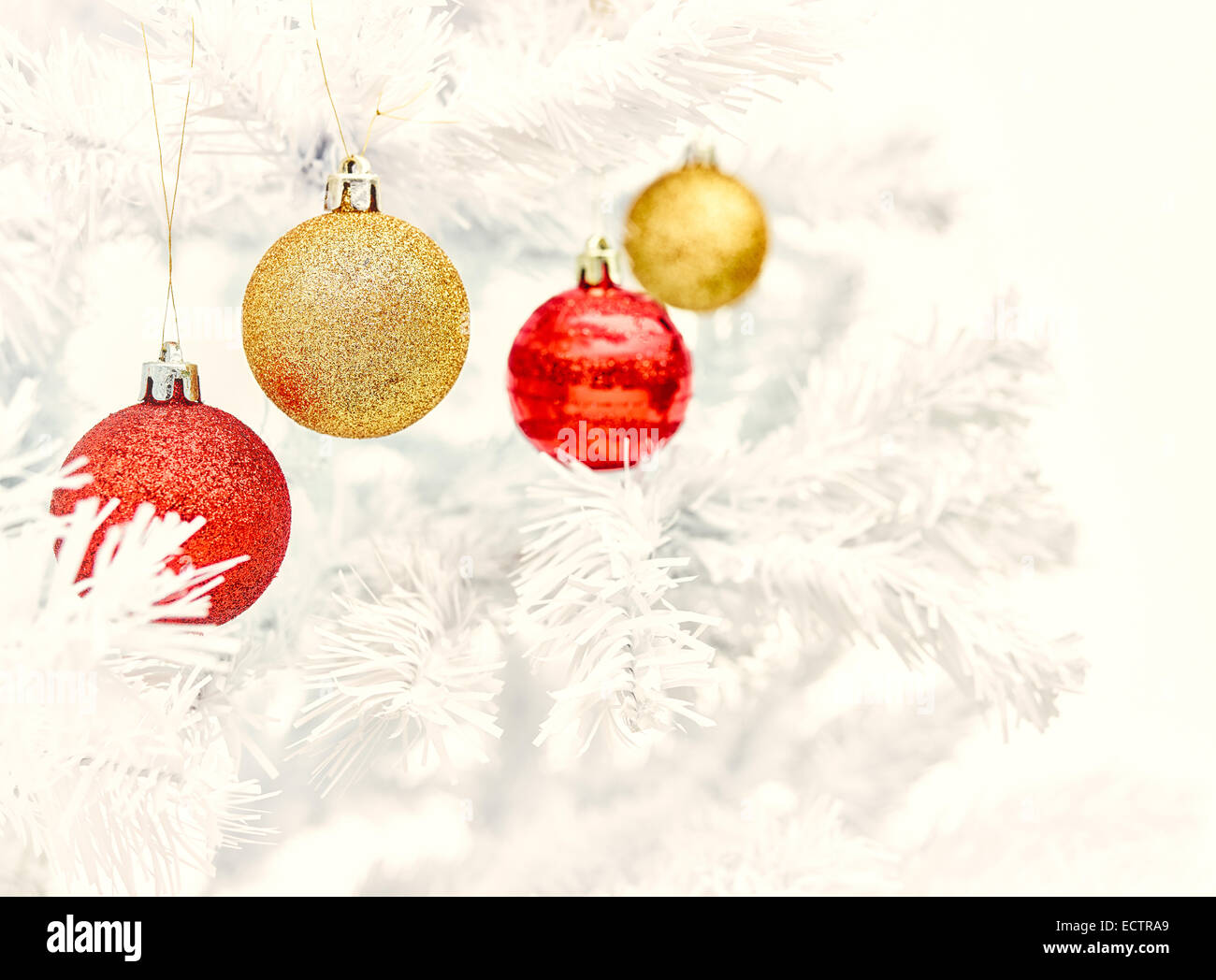 Rote und goldene Kugeln schmückt den weißen Weihnachtsbaum - Jahrgang getönt Stockfoto