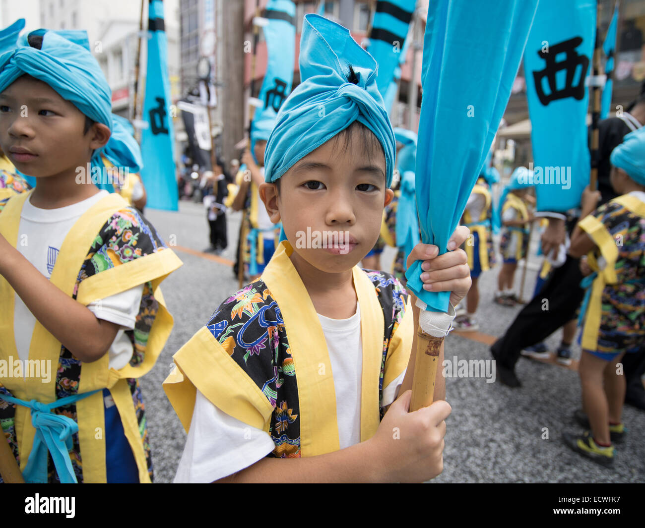 Kleinkinder tragen Fahnen vor der weltweit größte Tauziehen, Stadt Naha, Okinawa, Japan Stockfoto