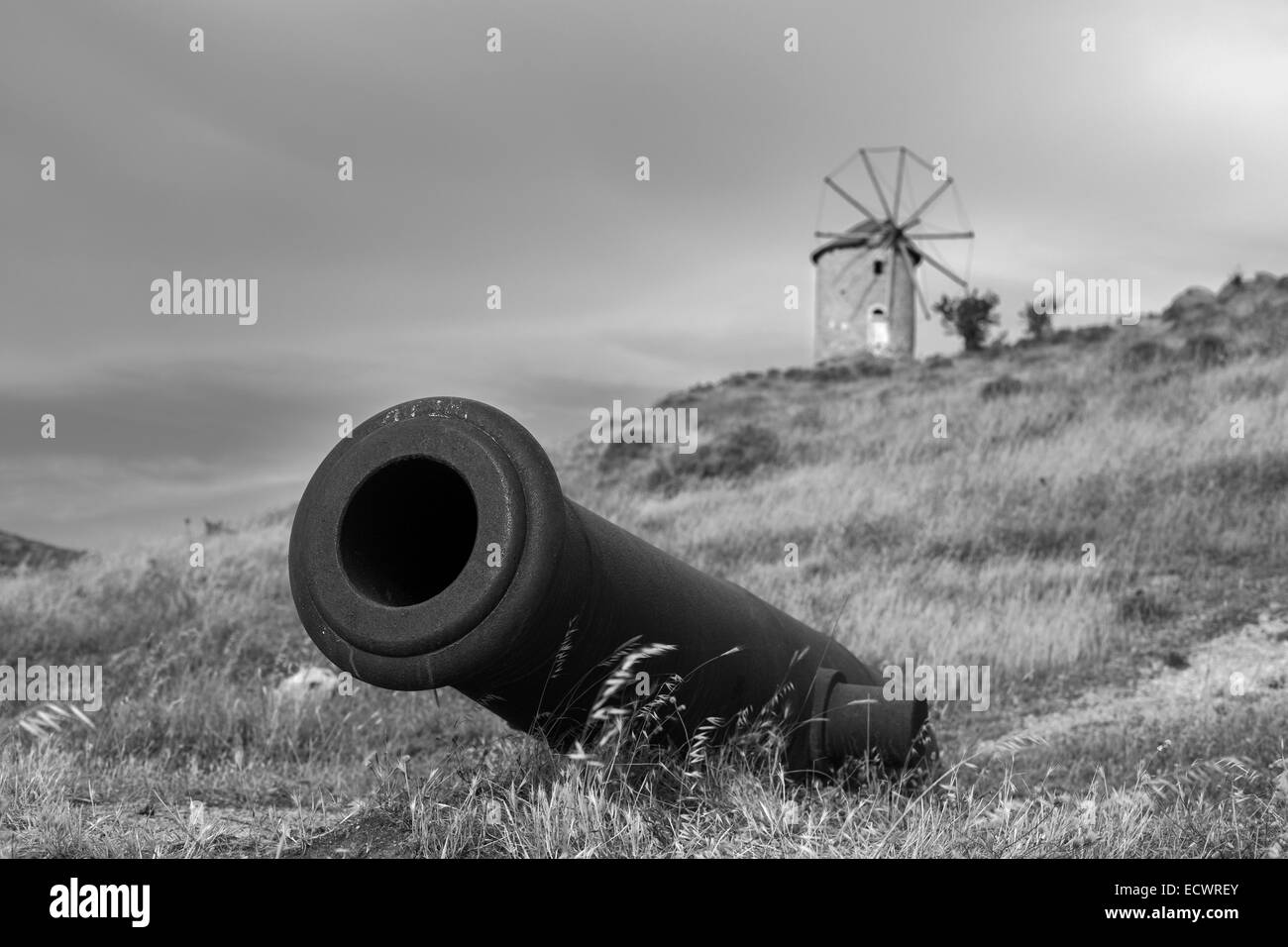 Historische alte Kanone mit Windmühle Hintergrund auf einer Wiese B&W horizontale Komposition Stockfoto