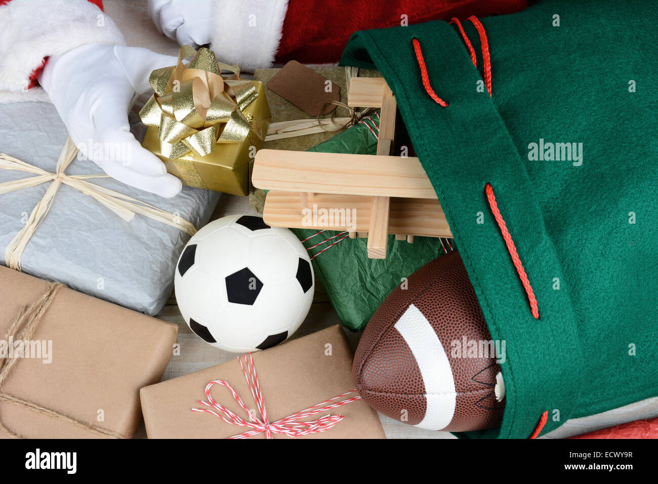 Nahaufnahme von Santa Claus seine Tasche mit Spielzeug und Geschenke zu füllen. Nur Santas Hände sind sichtbar. Verpackte Geschenke Fußball Stockfoto
