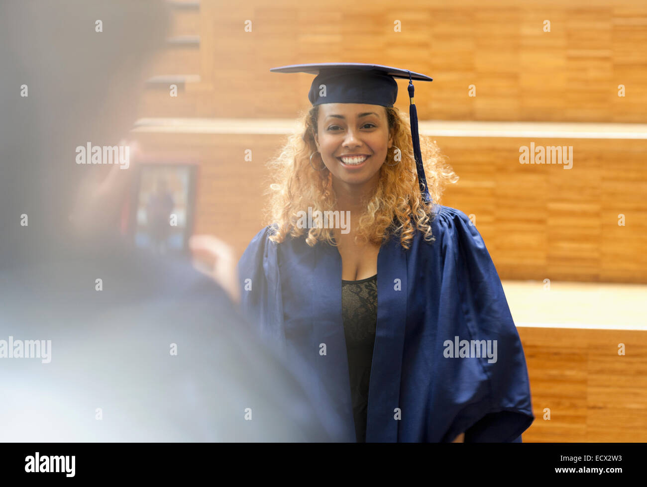 Studentin in Graduierung Kleid posieren für Bild-in-Universität Korridor Stockfoto