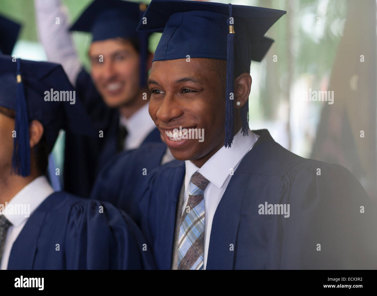 Lächelnde Studenten stehen im Freien während der Abschlussfeier Stockfoto