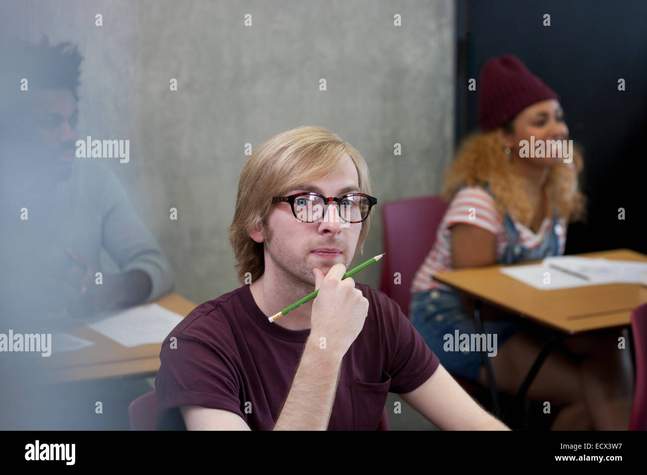 Porträt von Studenten sitzen am Schreibtisch mit Hand am Kinn Stockfoto
