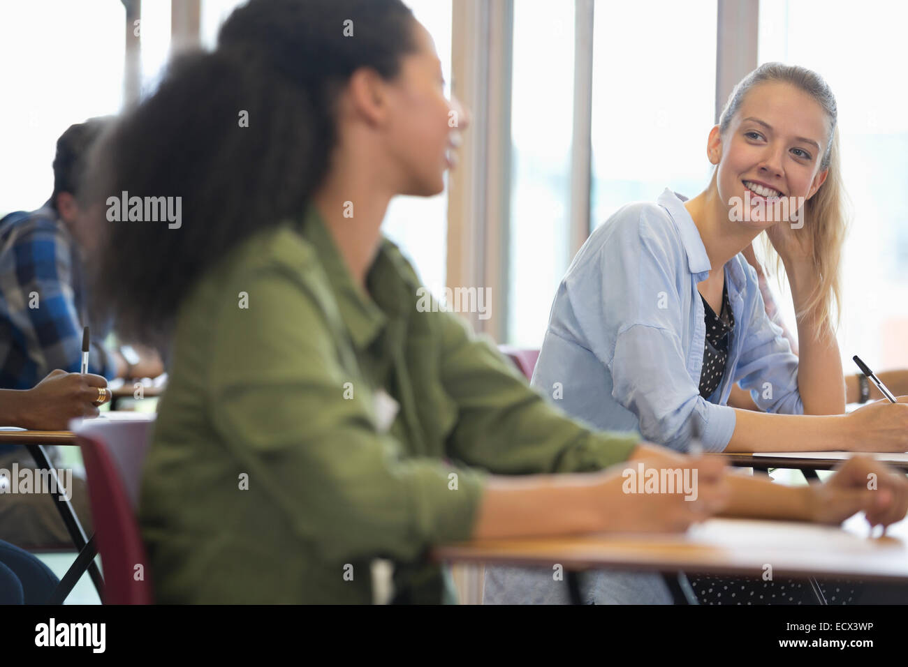 Lächelnde Studenten sprechen im Unterricht Stockfoto