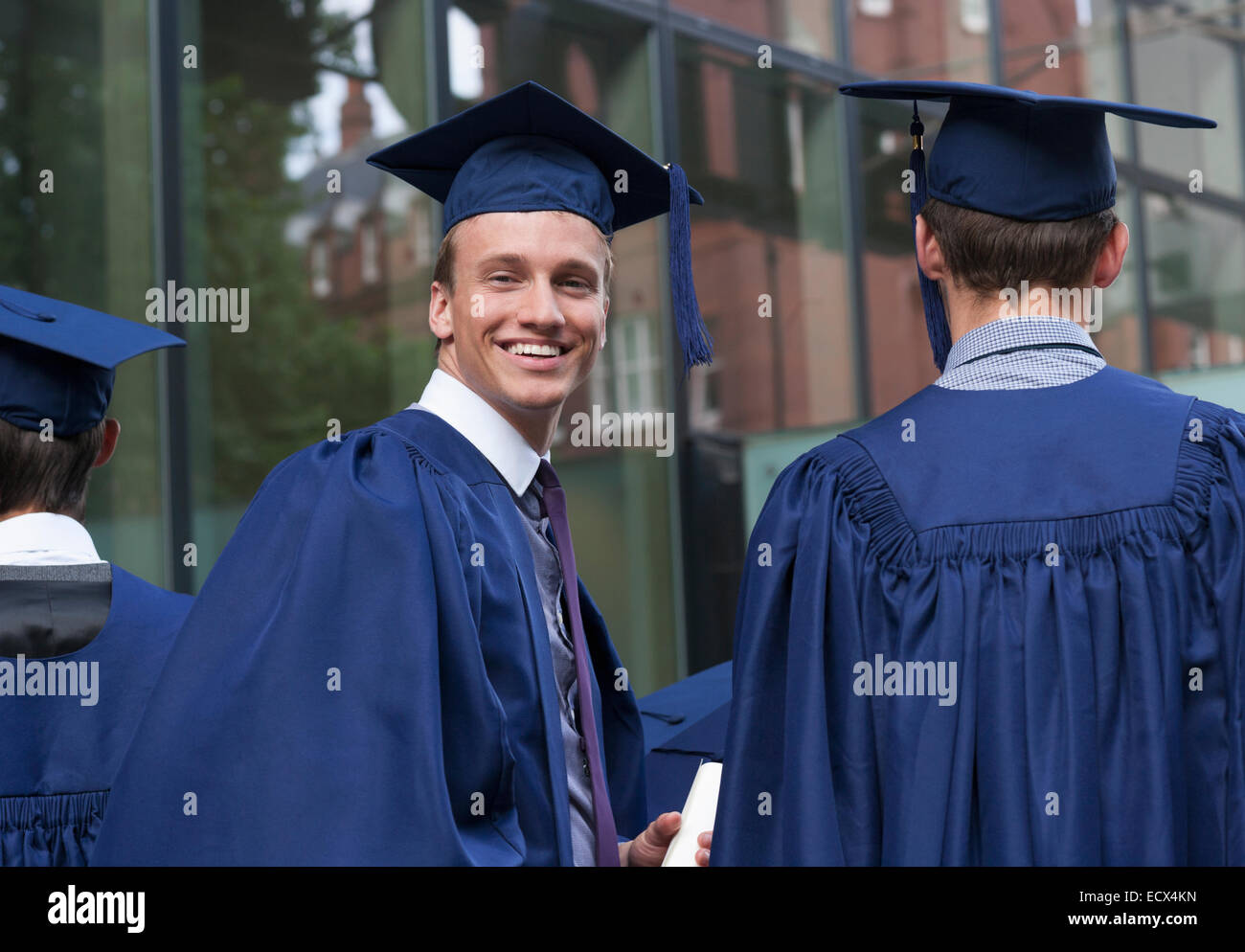 Lächelnde Studentin auf der Suche über die Schulter in die Kamera auf dem campus Stockfoto