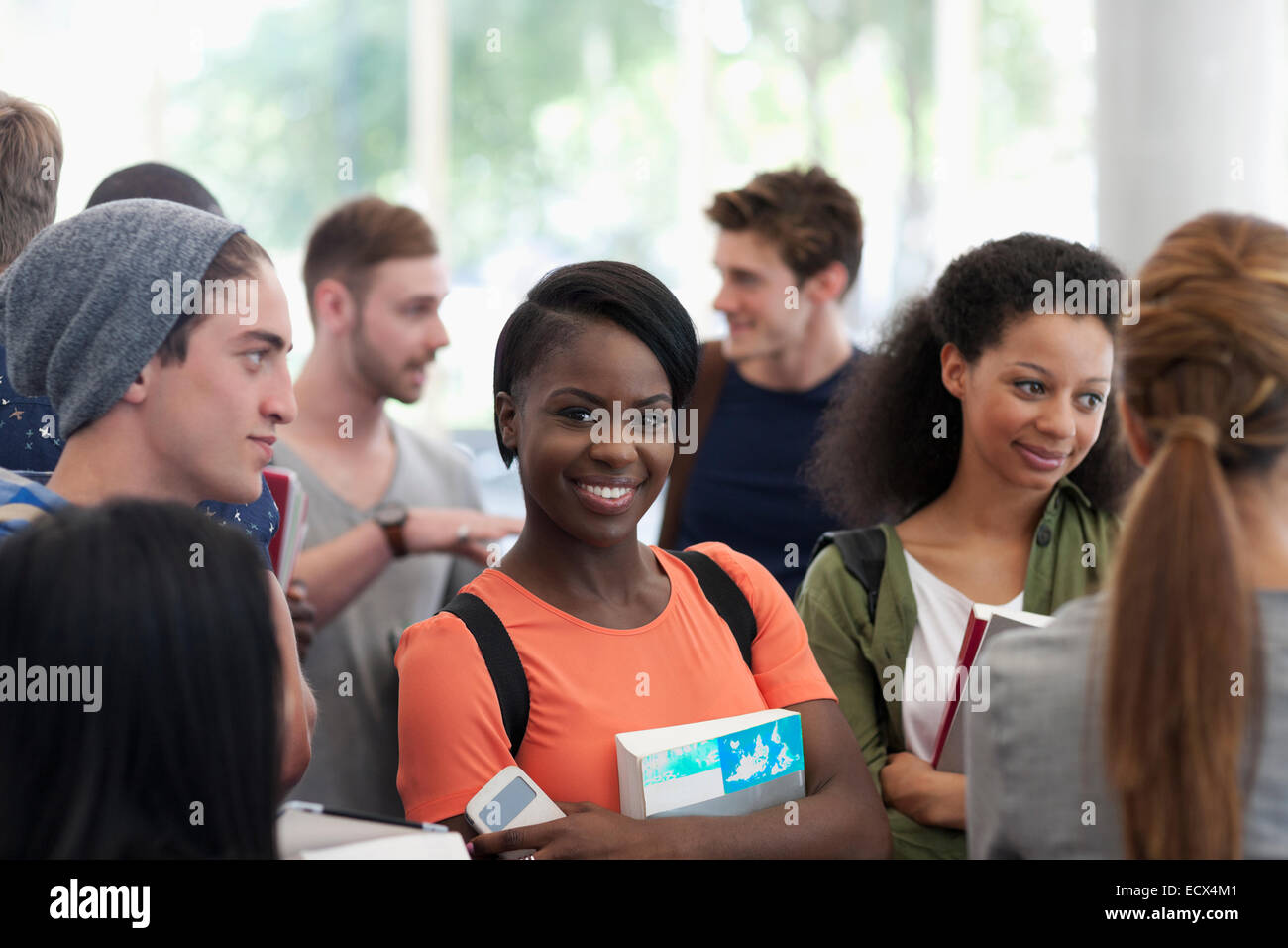 Universität Schüler tragen Buch lächelnd und Blick in die Kamera Stockfoto