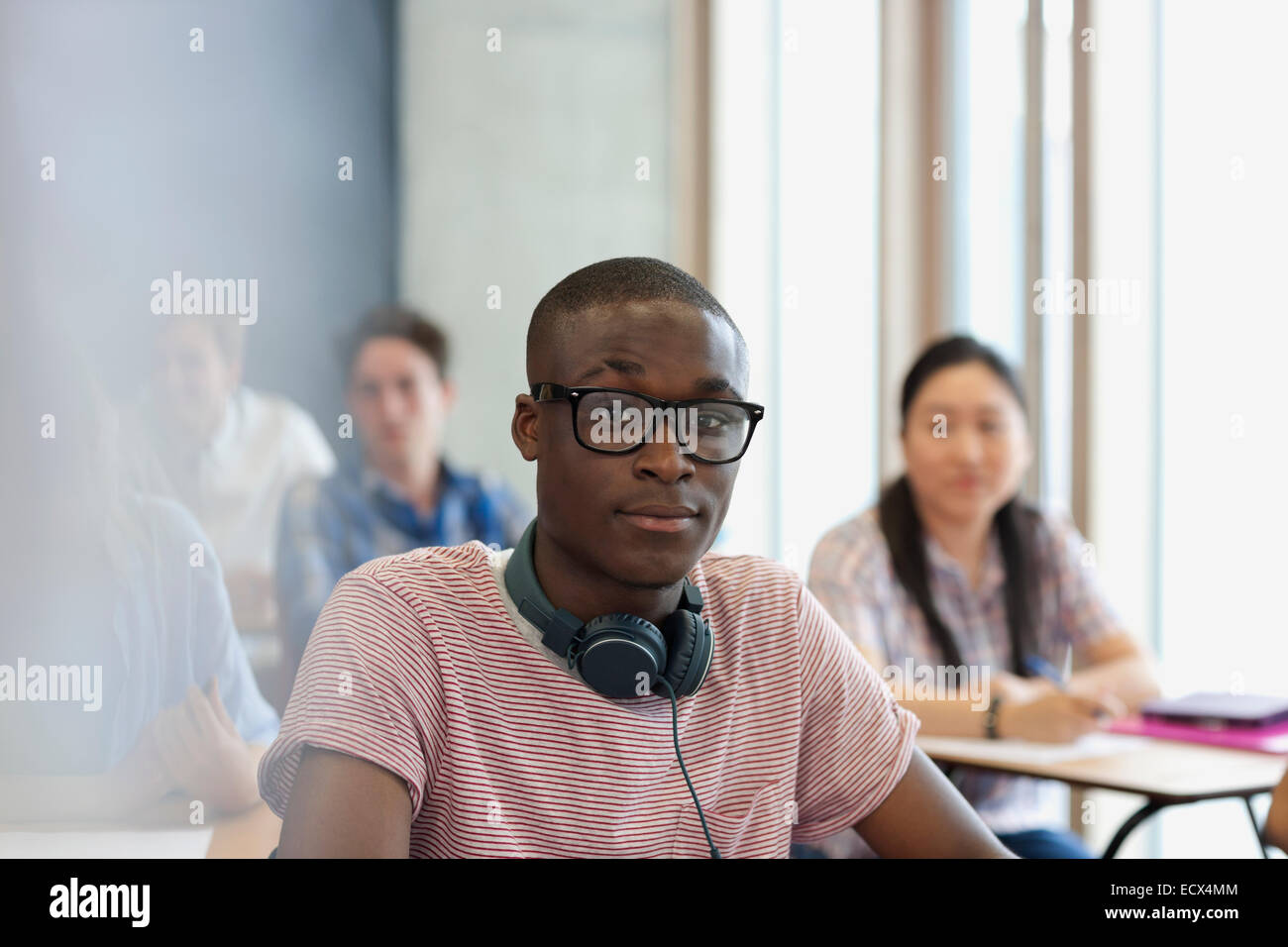 Männliche Studenten mit Brille und Kopfhörer um Hals, Blick in die Kamera während der Vorlesung Stockfoto