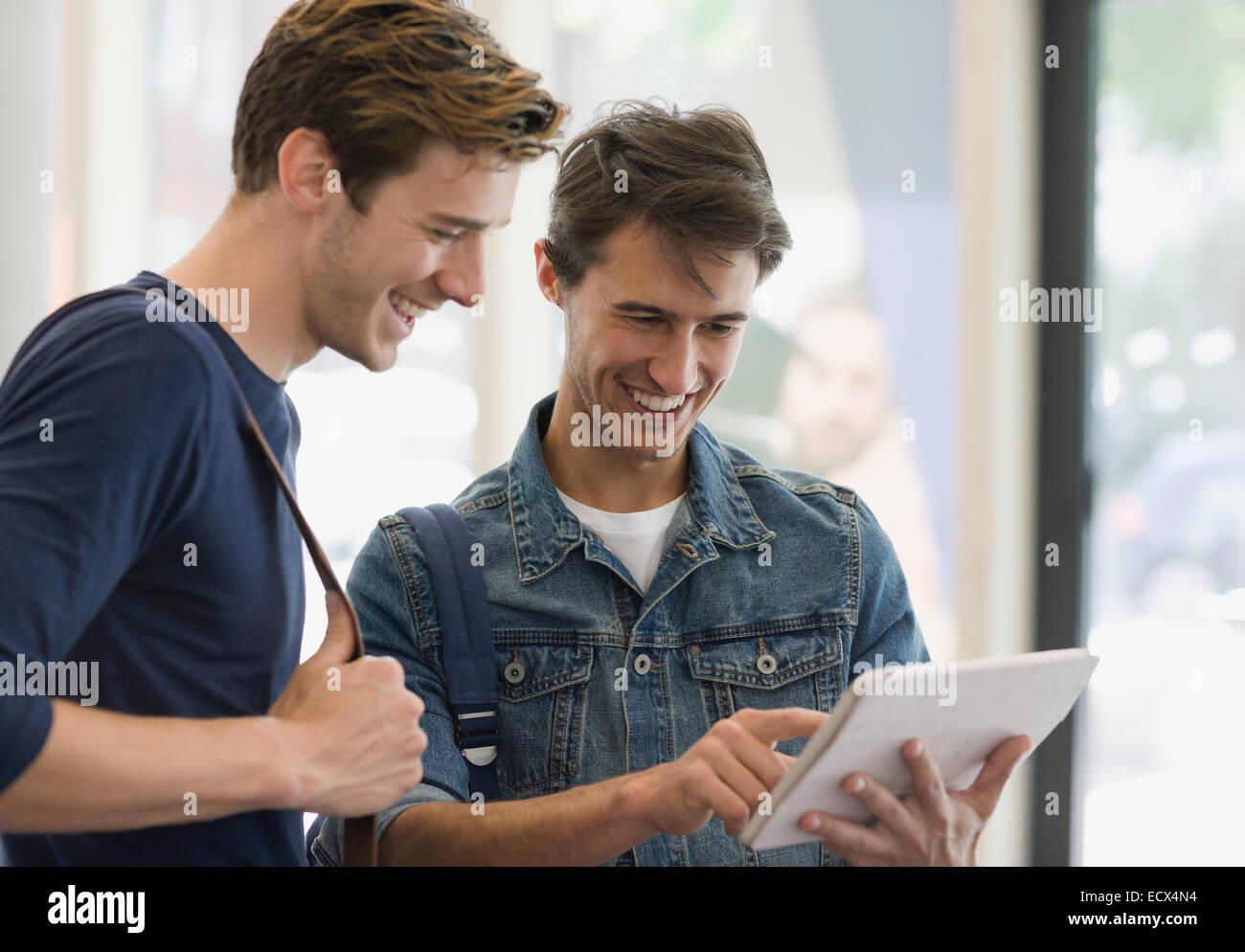 Zwei männliche Studenten betrachten digital-Tablette und lachen Stockfoto