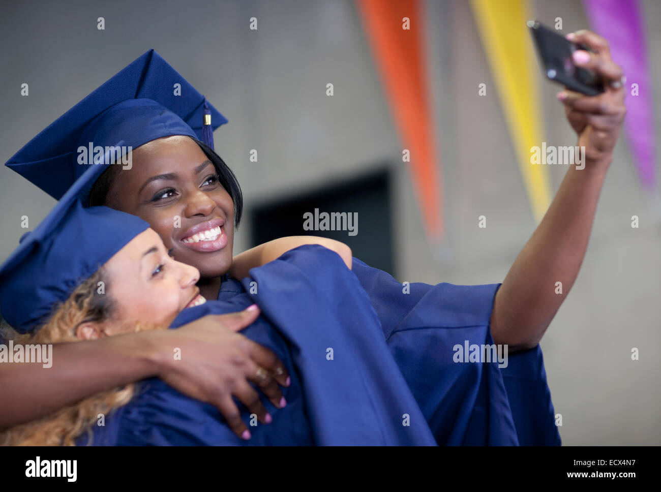 Zwei Studentinnen nehmen Selfie bei Studienabschluss lächelnd Stockfoto