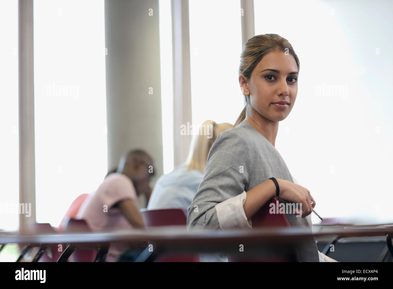 Studentin, Blick in die Kamera und sitzen am Schreibtisch während Vortrag Stockfoto