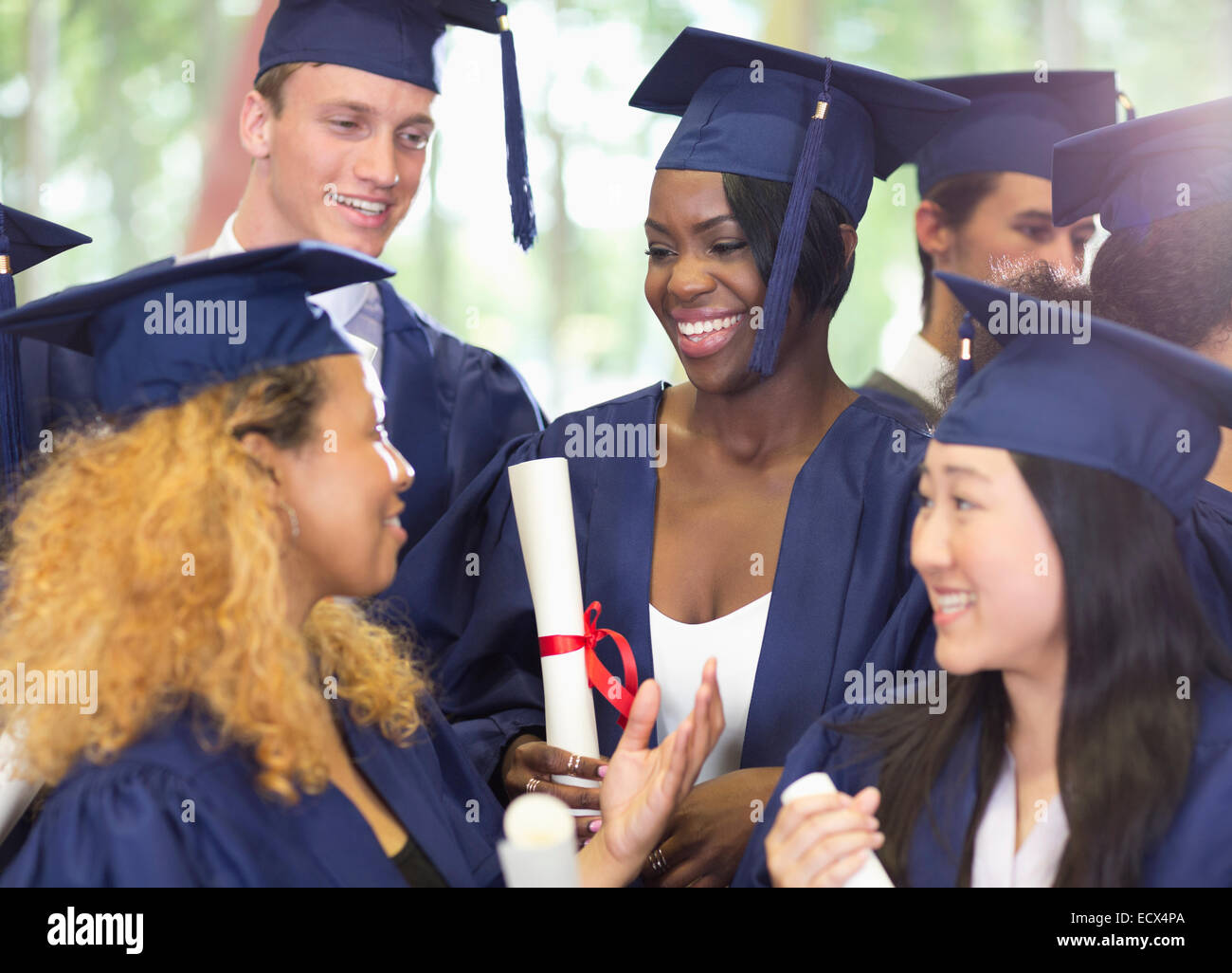 Gruppe von lächelnden Studenten Graduierung Kleidung miteinander zu reden Stockfoto
