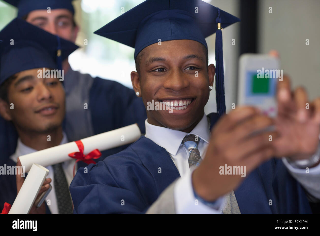 Lächelnd männlichen Studenten tragen Graduierung Kleider nehmen Selfie mit Freunden Stockfoto