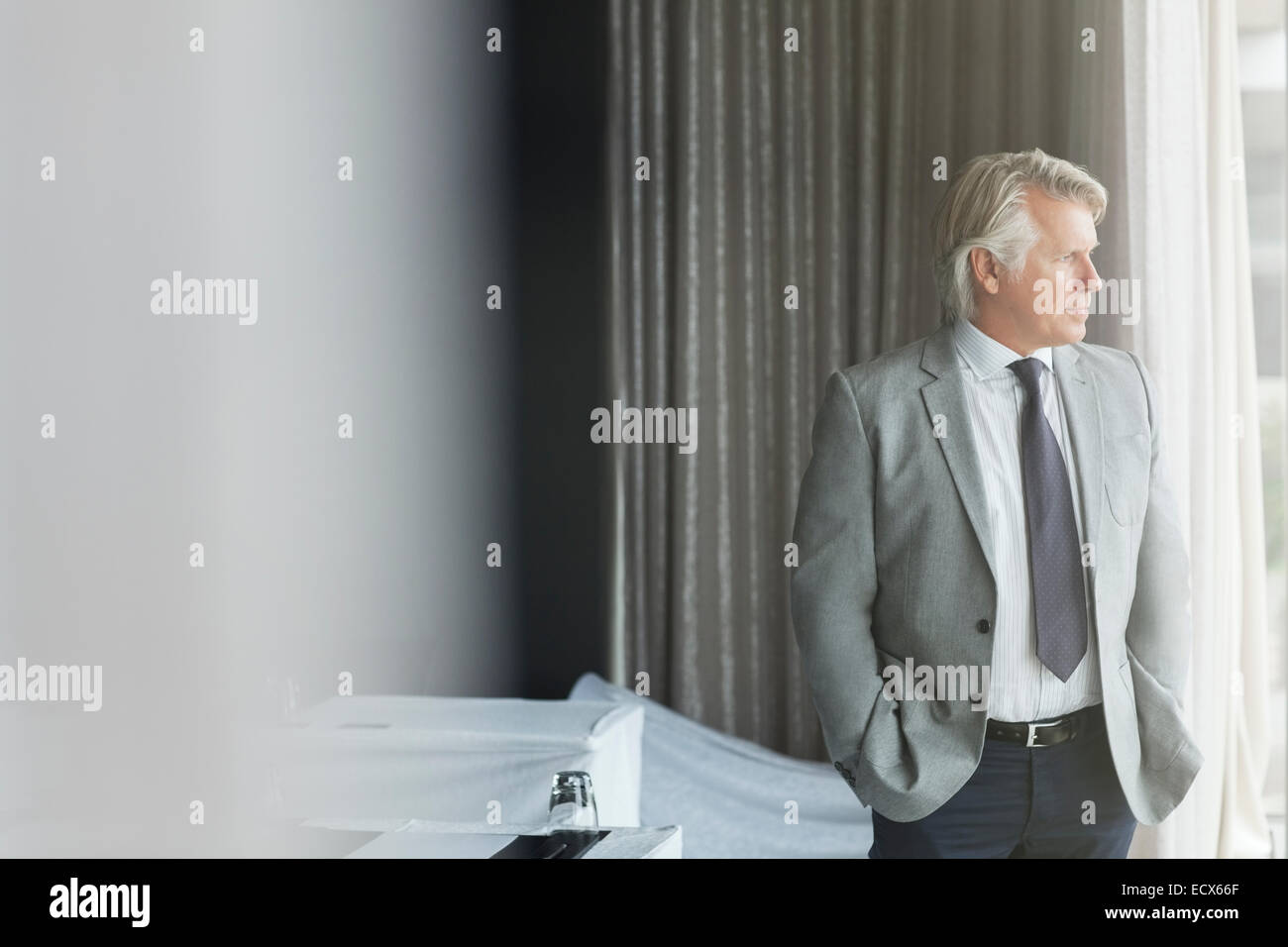 Porträt der Geschäftsmann mit Händen in den Taschen im Konferenzraum stehen, Blick aus Fenster Stockfoto