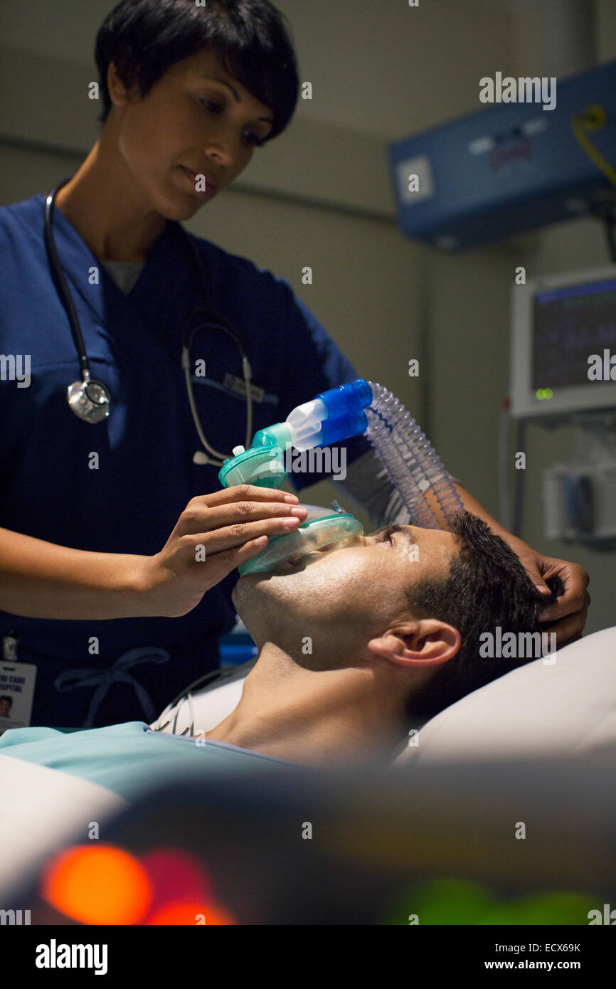 Ärztin mit Maske betäuben Mitte erwachsenen Mannes in Spitalabteilung Stockfoto
