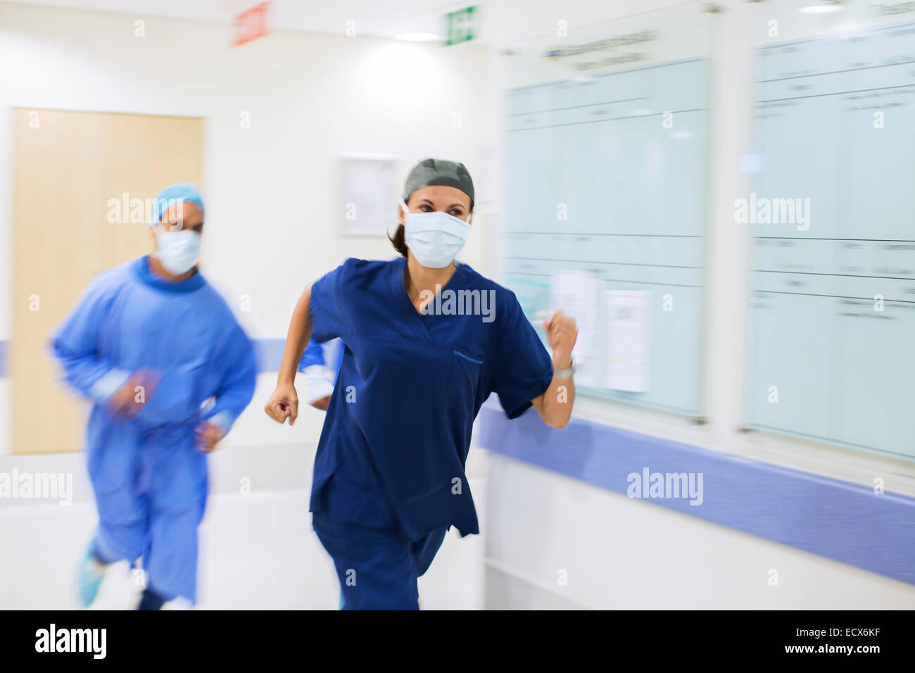 Medizinisches Personal tragen scheuert und chirurgische Masken Rauschen durch Krankenhausflur Stockfoto