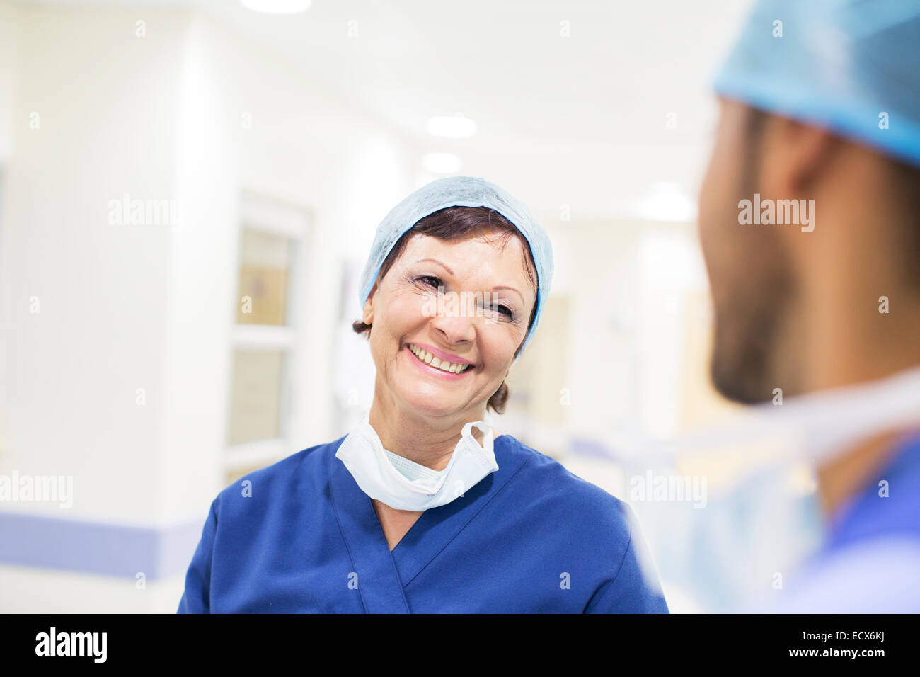 Ärzte tragen chirurgische Kappen im Krankenhausflur stehen und reden Stockfoto