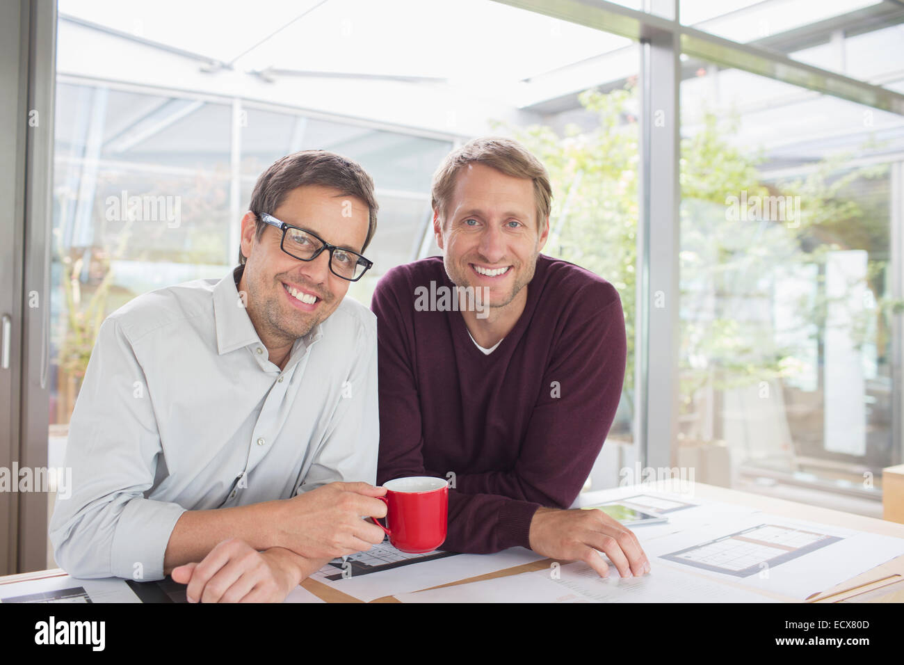 Geschäftsleute, die lächelnd am Schreibtisch Stockfoto