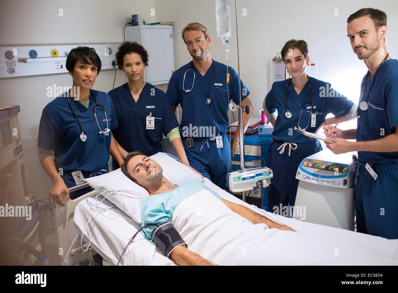 Ärzteteam herumstehen lächelnd Patienten liegen im Bett auf Intensivstation Stockfoto