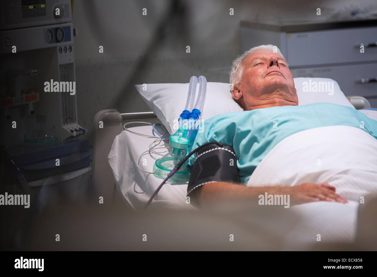 Patienten liegen im Bett neben Sauerstoffmaske auf Intensivstation Stockfoto