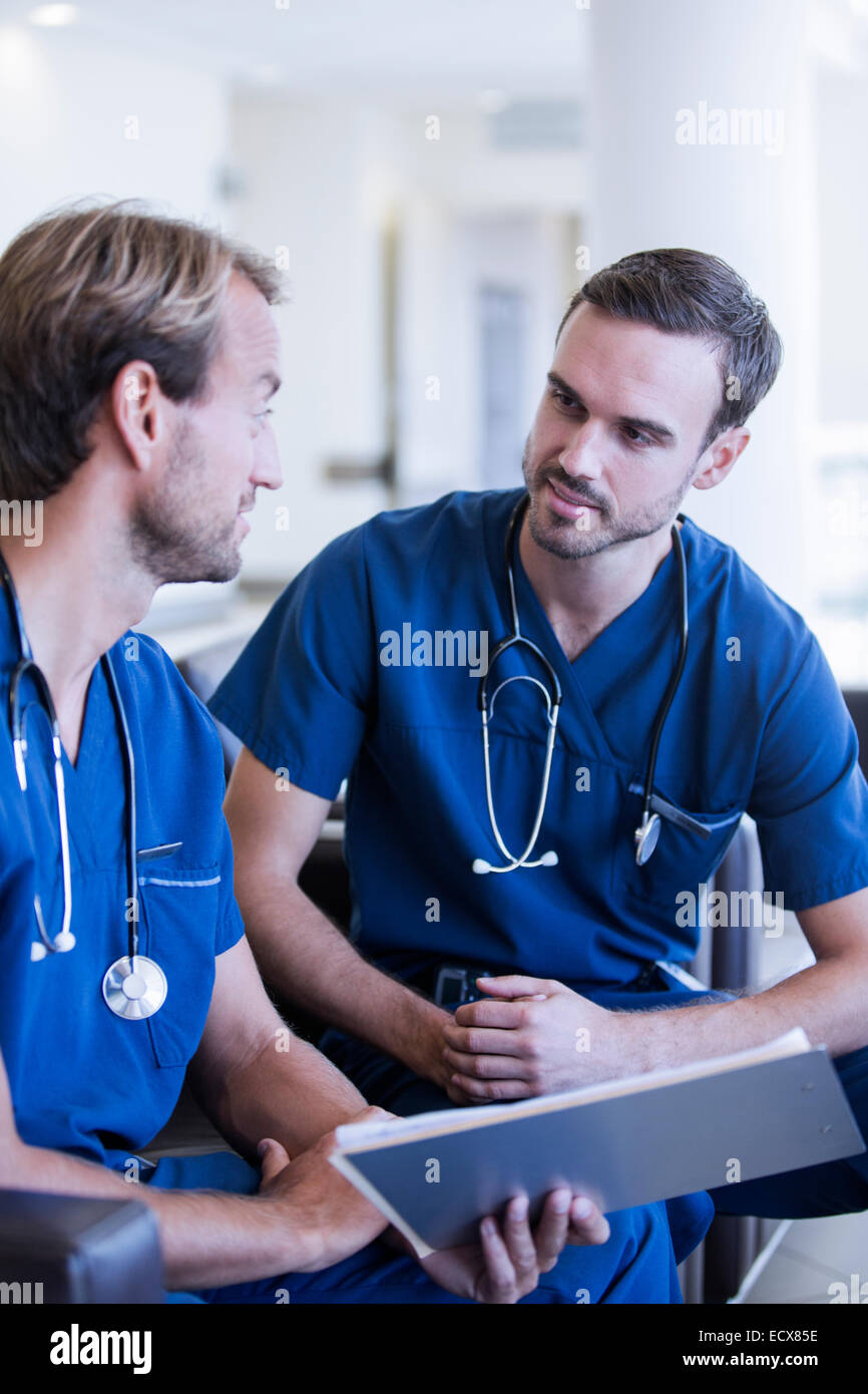 Zwei männliche Ärzte mit Stethoskope, Scrubs – Die Anfänger tragen sprechen im Krankenhaus Stockfoto