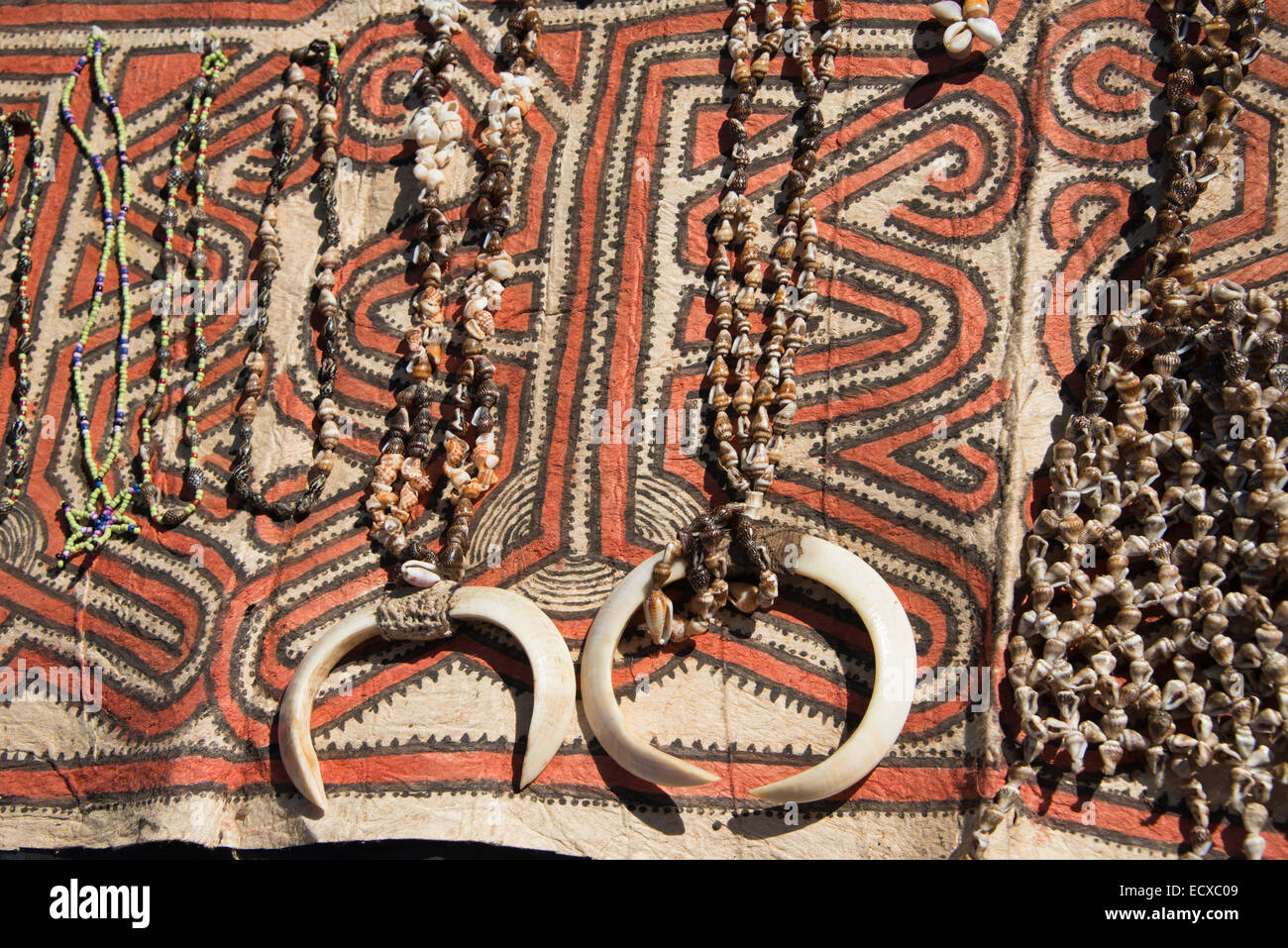 Papua Neu Guinea, Tufi. Muschelketten mit Wildschwein Stoßzähne auf traditionelle Handarbeit Tapa Tuch, aus dem Papier Maulbeerbaum hergestellt. Stockfoto