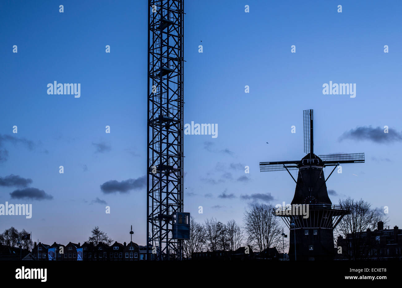 Bau Kran und niederländischen Wind Mühle und Stadt-Silhouette vor Abendhimmel Stockfoto