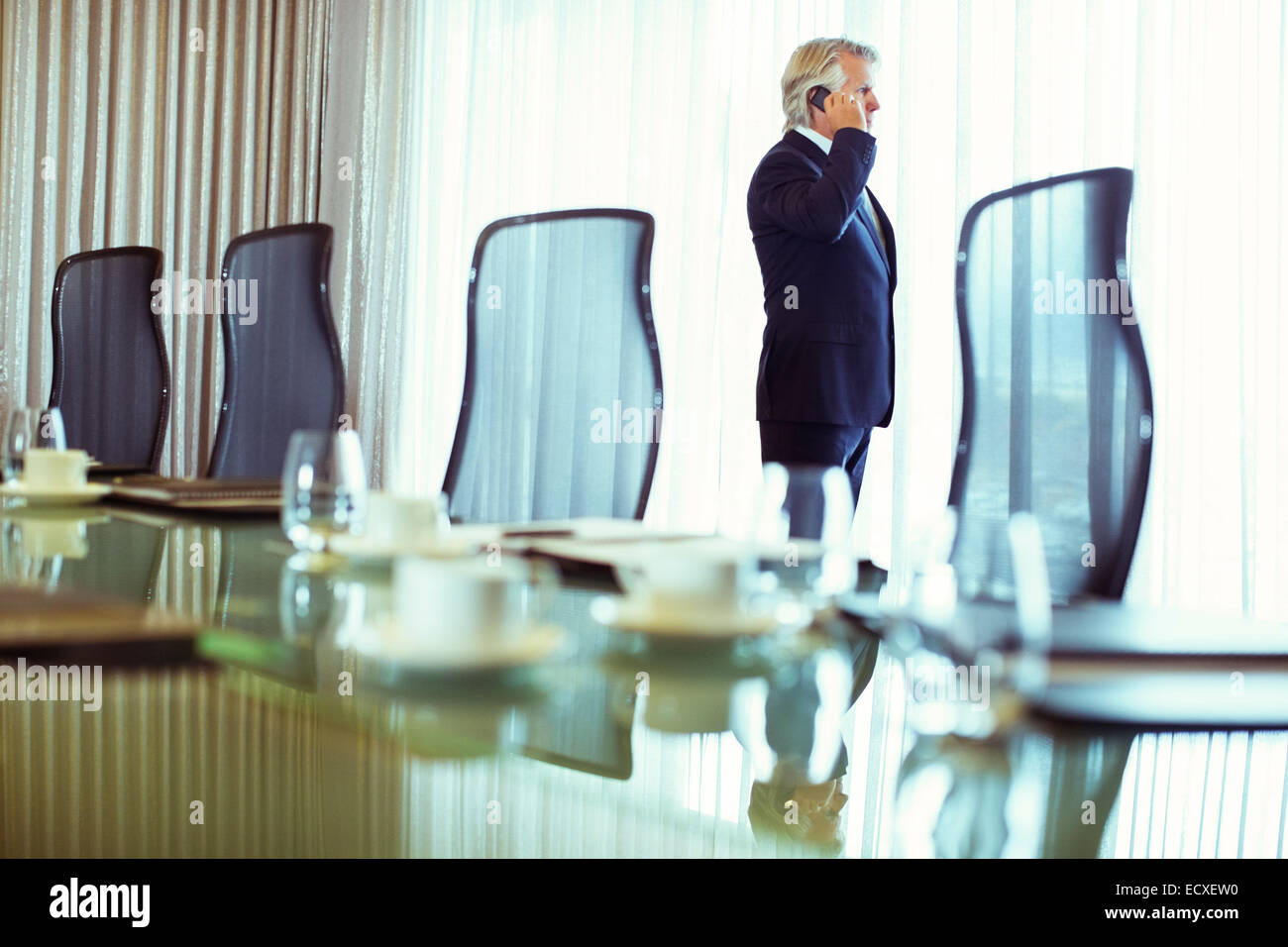 Geschäftsmann Blick aus Fenster und mit Handy im Konferenzraum Stockfoto