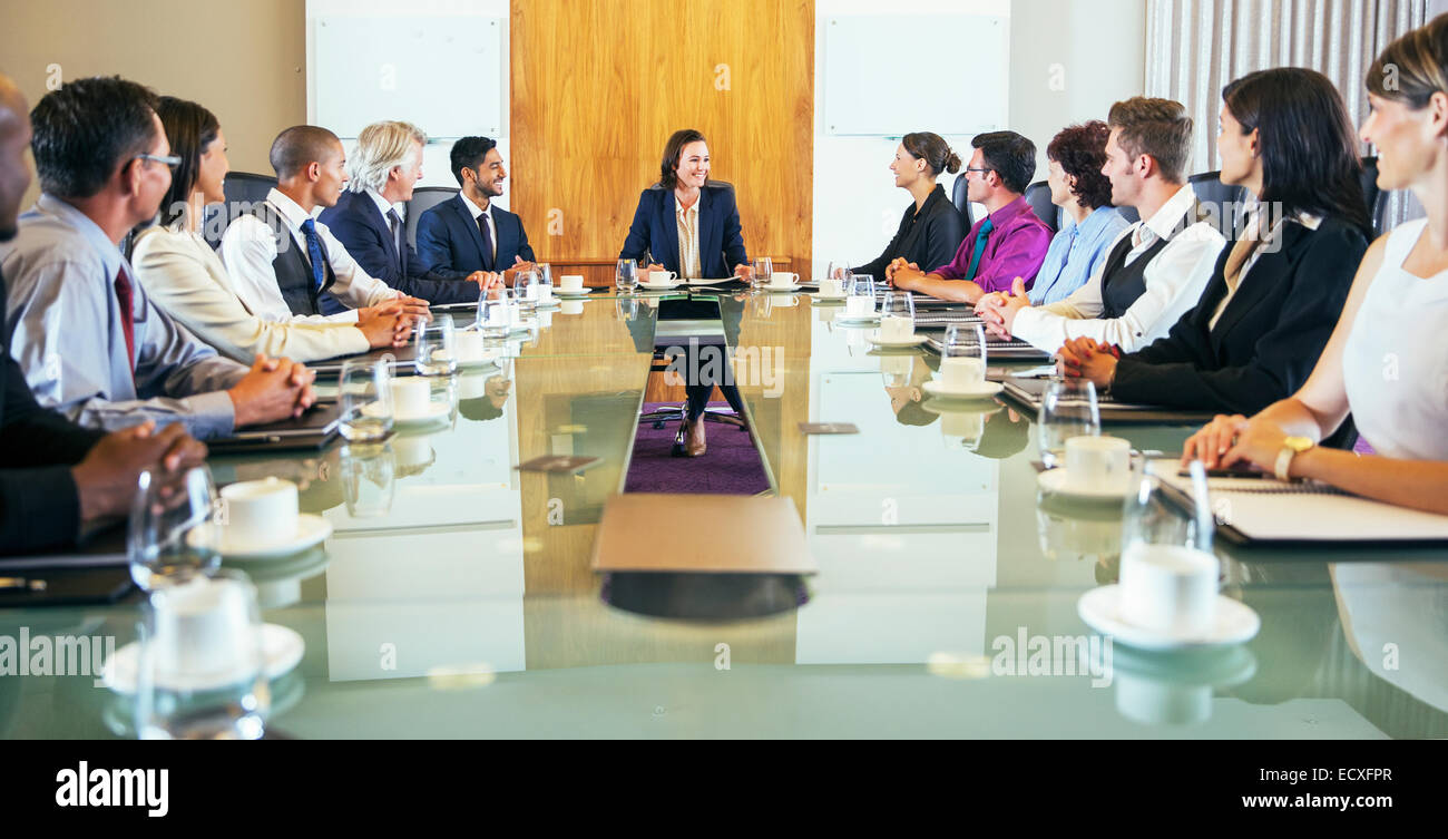 Konferenzteilnehmer, die junge Frau sitzt am Kopf des Konferenztisches betrachten Stockfoto