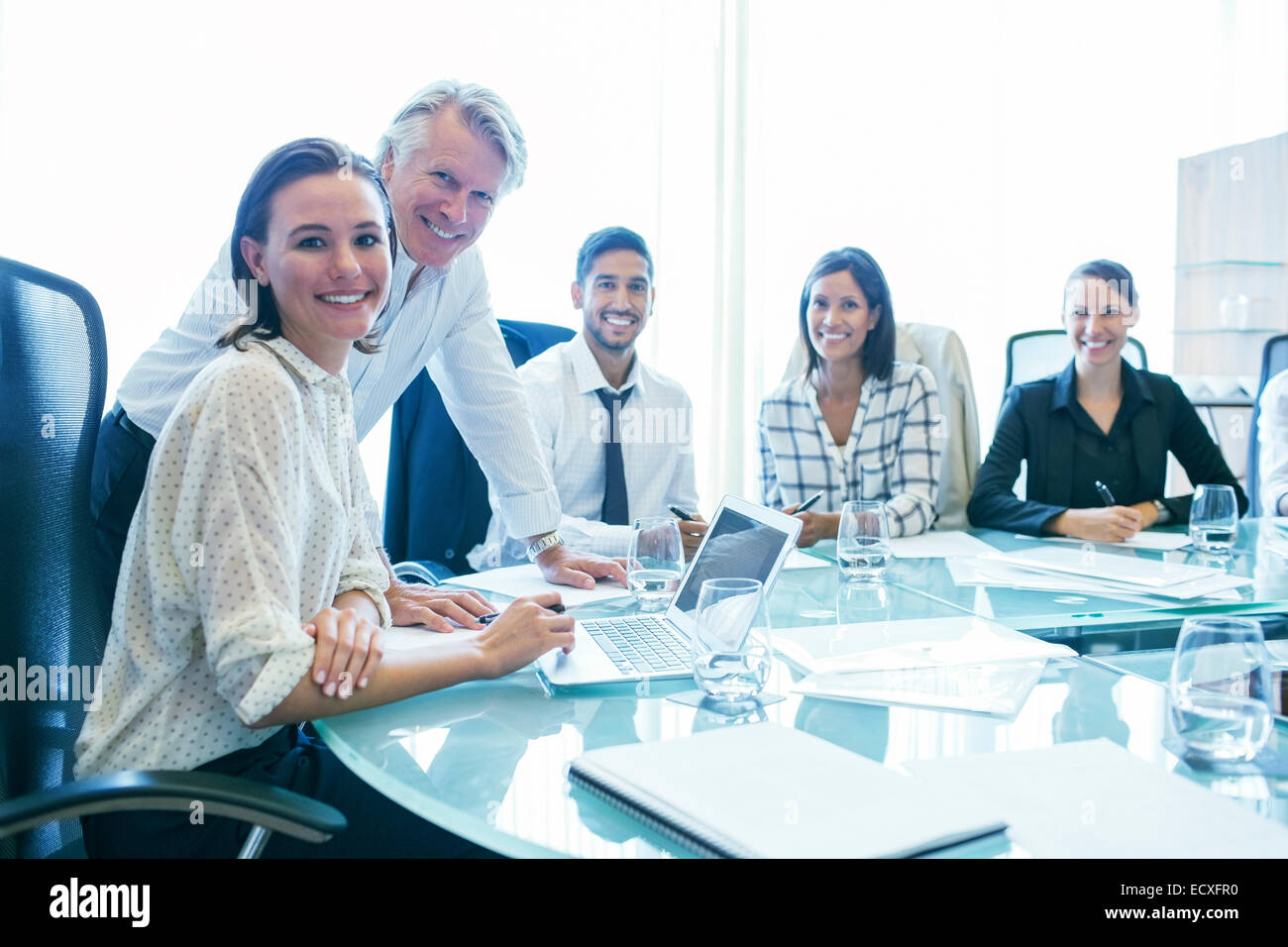 Drei Unternehmerinnen und zwei Geschäftsleute sitzen am Konferenztisch, Lächeln Stockfoto