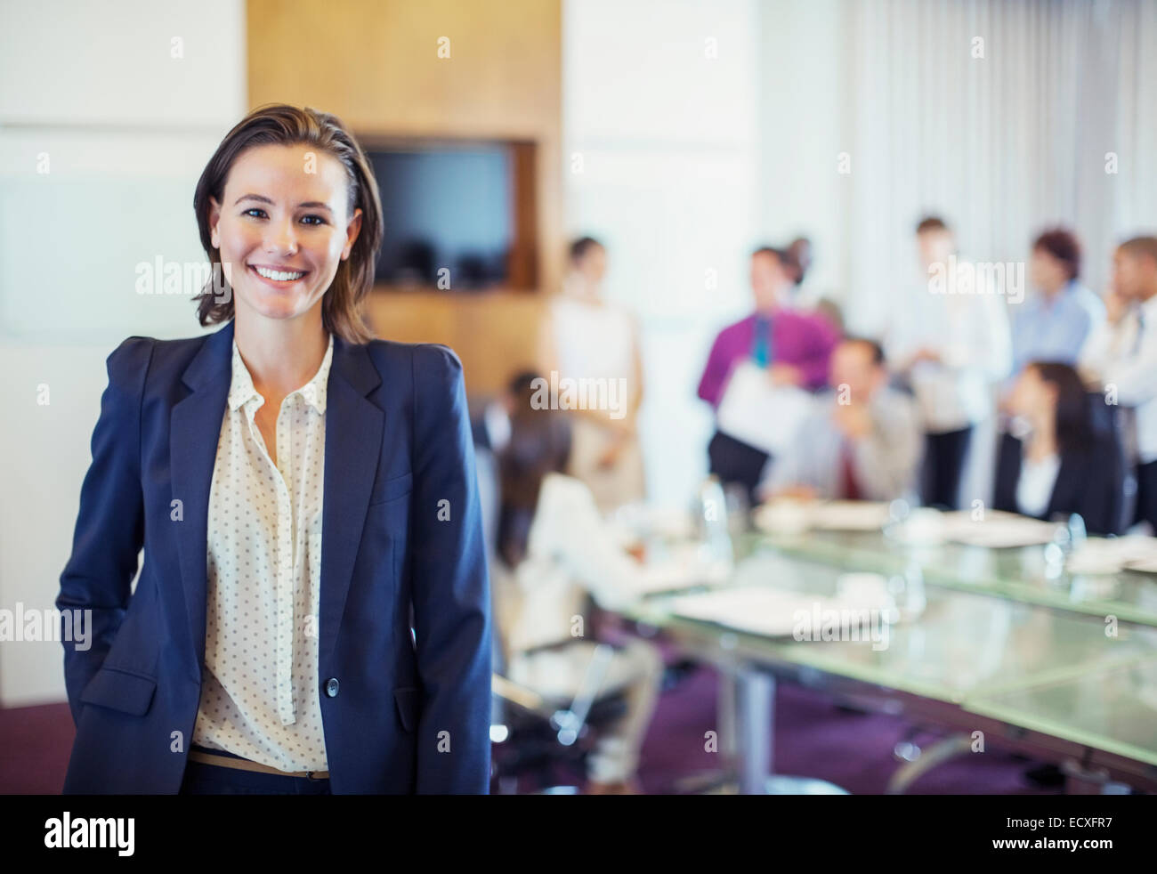 Porträt des jungen Geschäftsfrau lächelnd im Konferenzraum, Menschen im Hintergrund Stockfoto