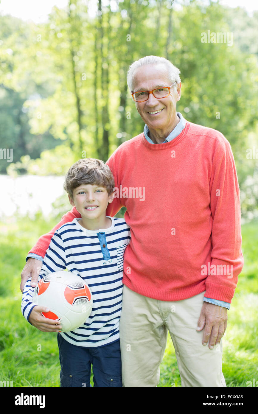 Großvater und Enkel, die lächelnd im Freien mit Fußball Stockfoto