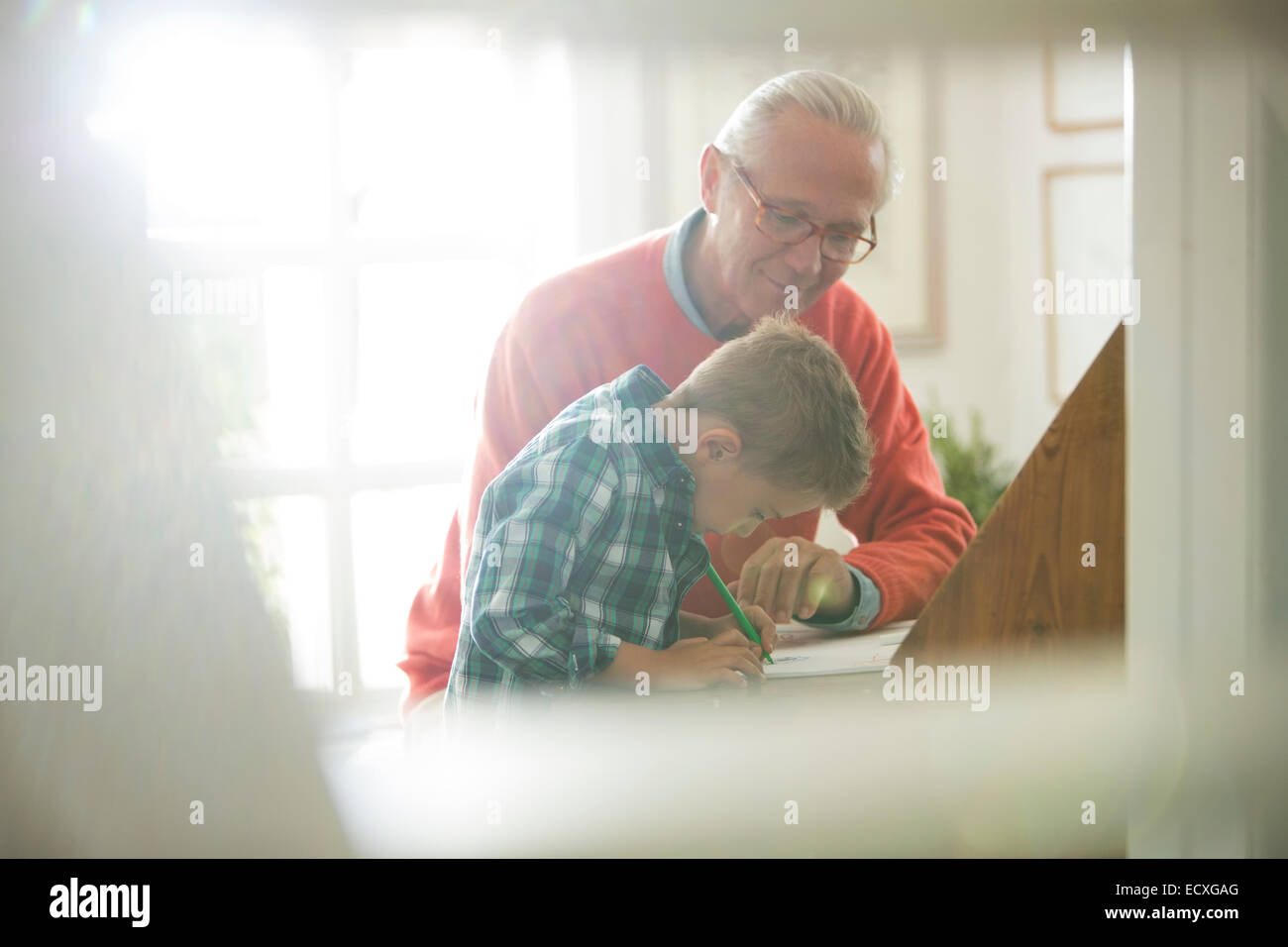 Großvater und Enkel schreiben am Schreibtisch Stockfoto