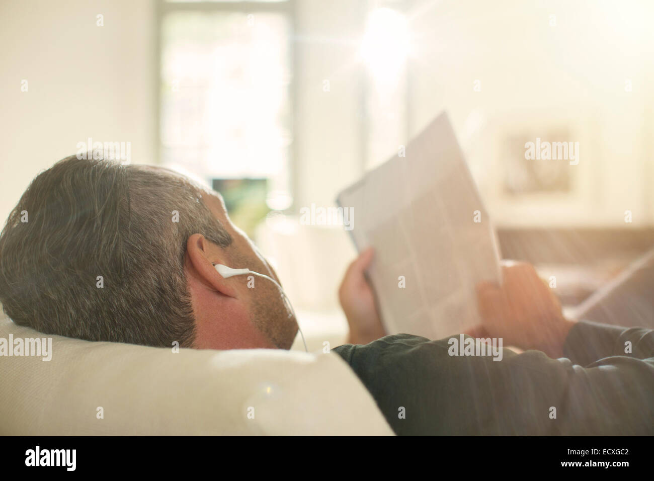 Älterer Mann hören Kopfhörer auf sofa Stockfoto