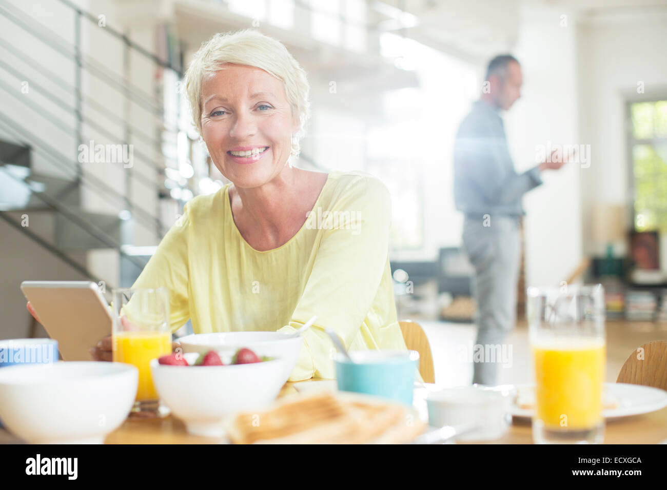 Ältere Frau mit digital-Tablette am Frühstückstisch Stockfoto