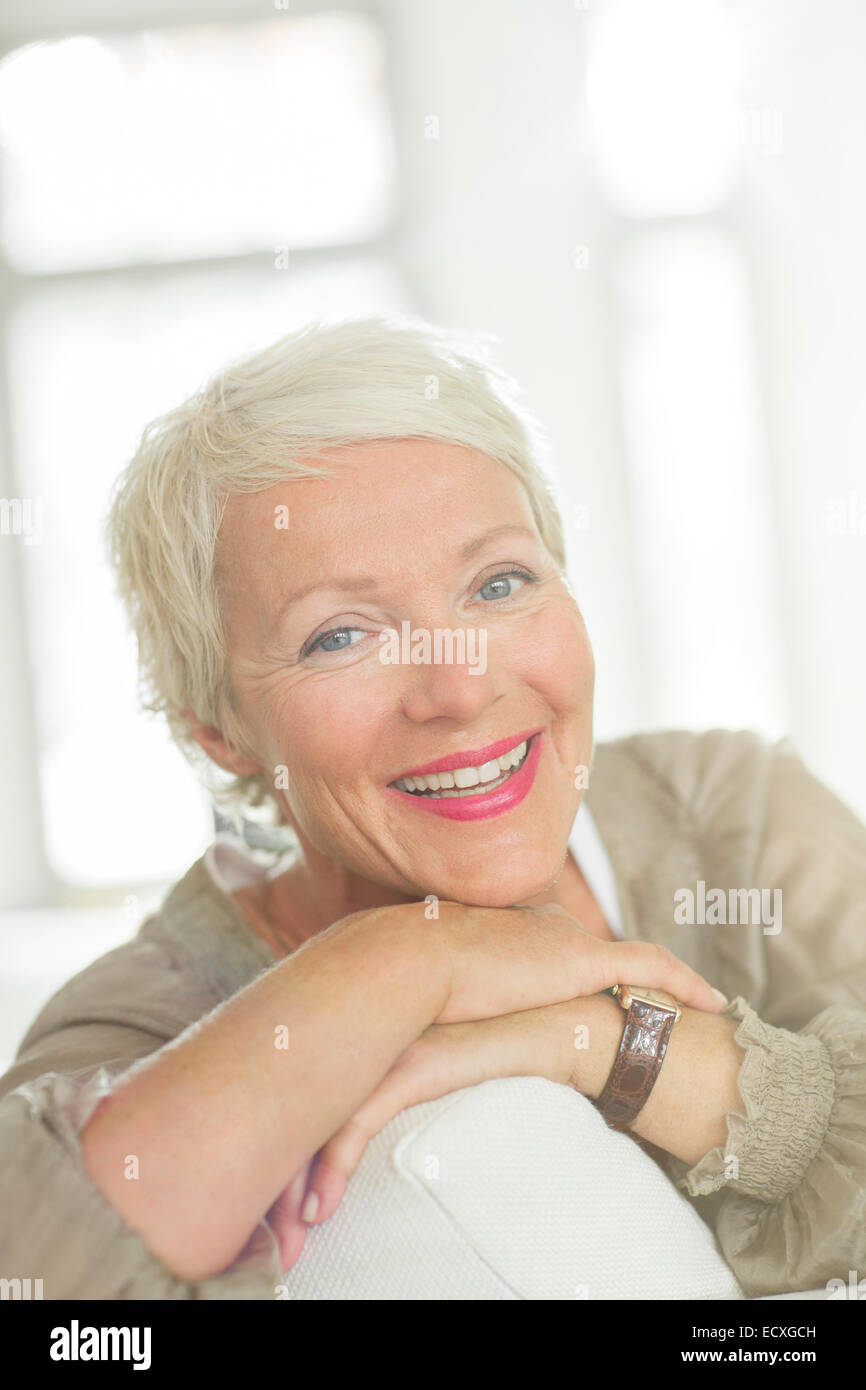 Ältere Frau lächelnd auf sofa Stockfoto