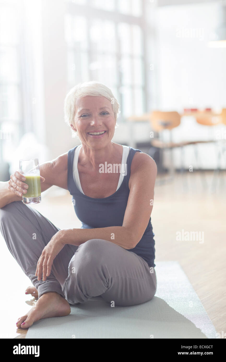 Ältere Frau trinken Saft auf Gymnastikmatte Stockfoto