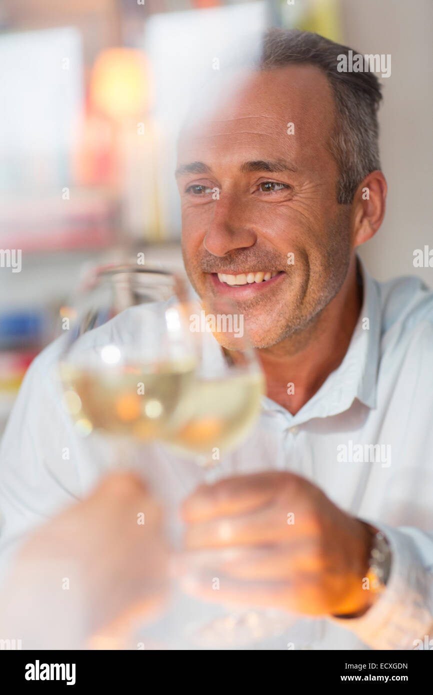 Lächelnder älterer Mann Toasten mit Weißwein Stockfoto