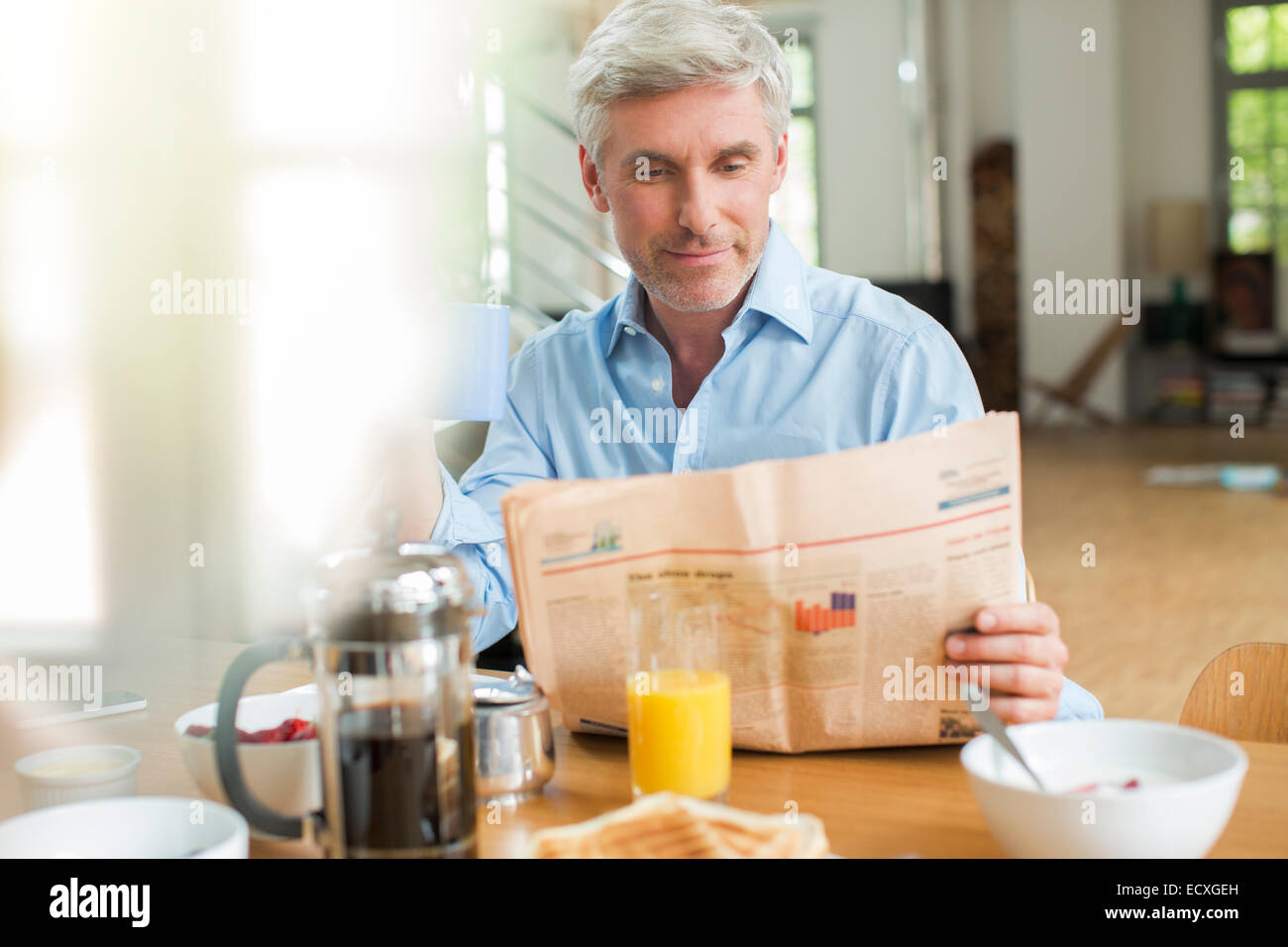 Ältere Mann liest Zeitung am Frühstückstisch Stockfoto