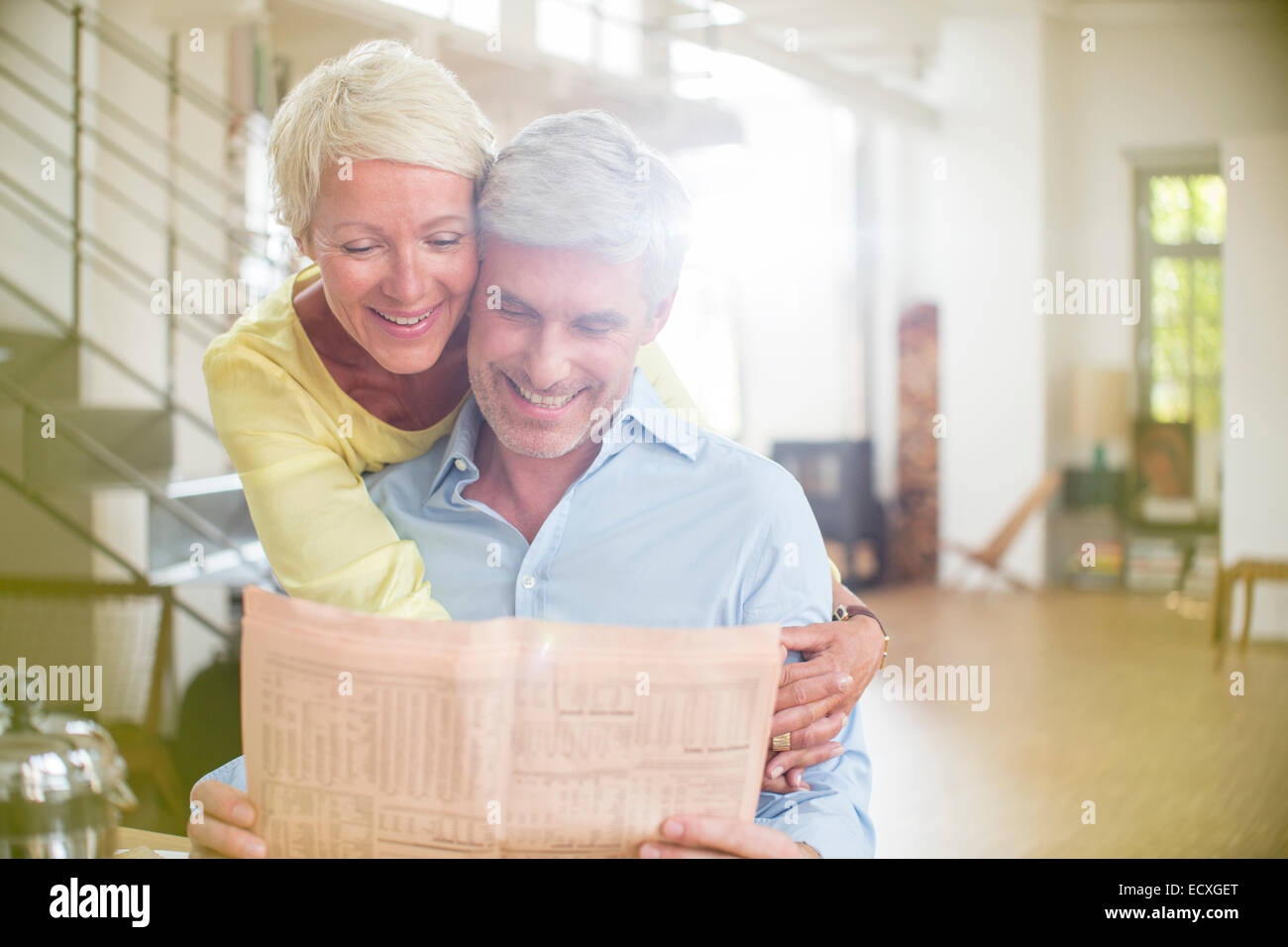 Ältere Frau umarmt Mann lesen Zeitung Stockfoto