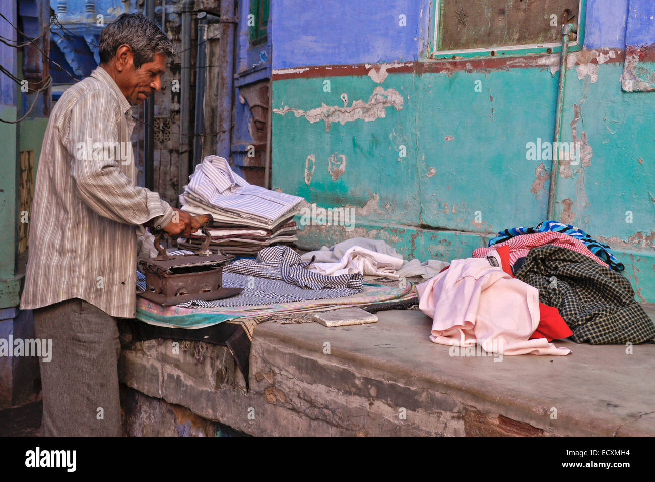 Mann ein Bügeleisen/-Brett Kleidung vor seinem Haus in die blaue Stadt Jodhpur, Rajasthan, Indien Stockfoto
