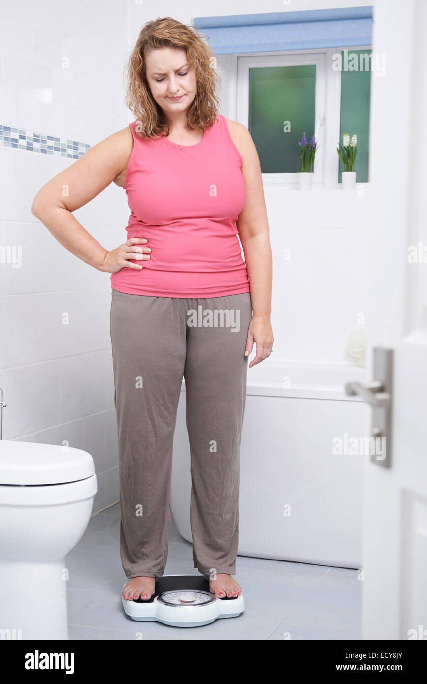 Übergewichtige Frau wiegen sich auf die Waage im Badezimmer Stockfoto