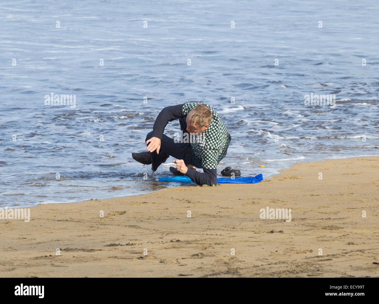 Mann dösen am Strand wird von der Flut getränkt. Stockfoto