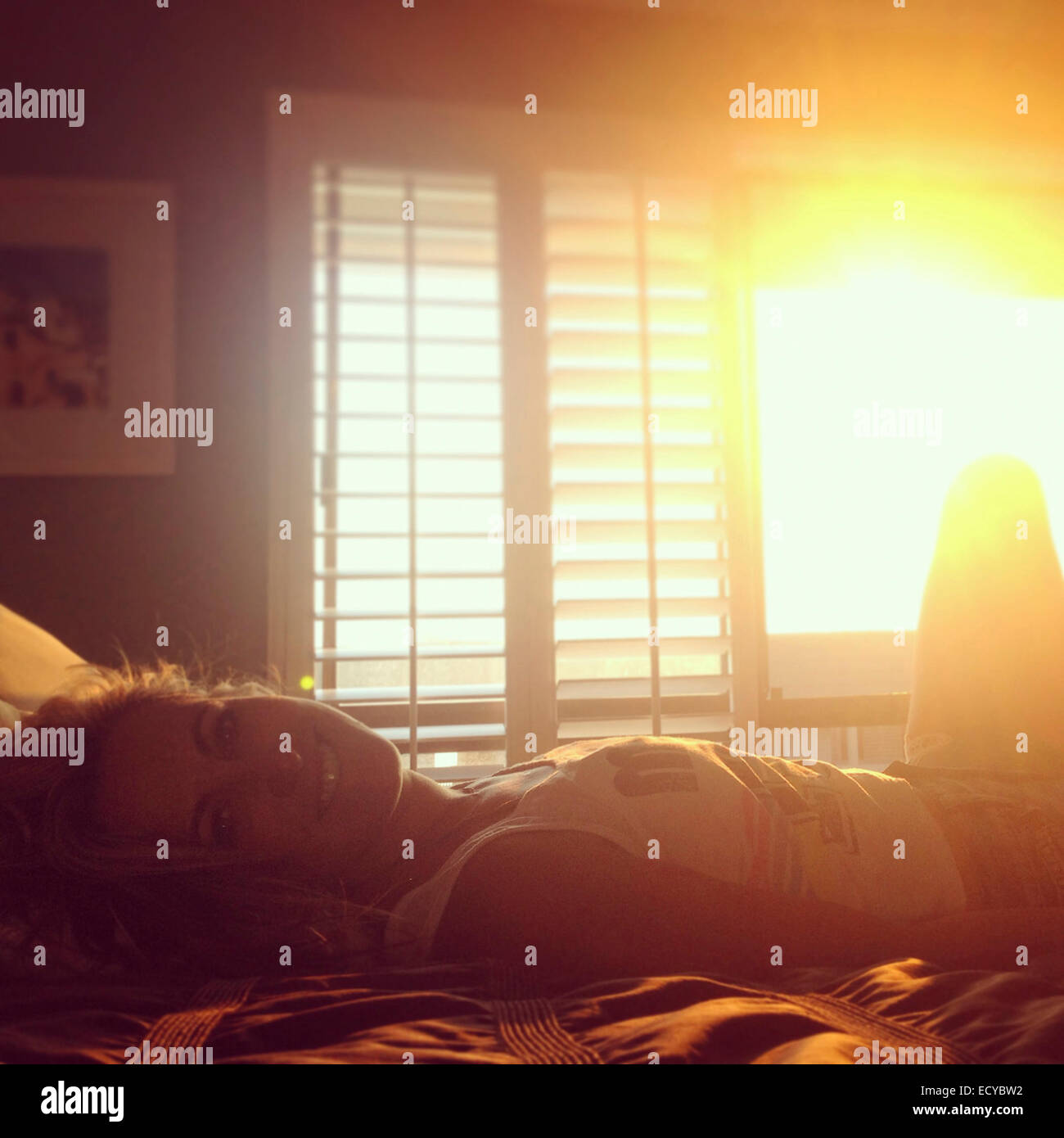 Lächelnde kaukasischen Frau auf Bett - Smartphone-aufgenommenes Stockfoto